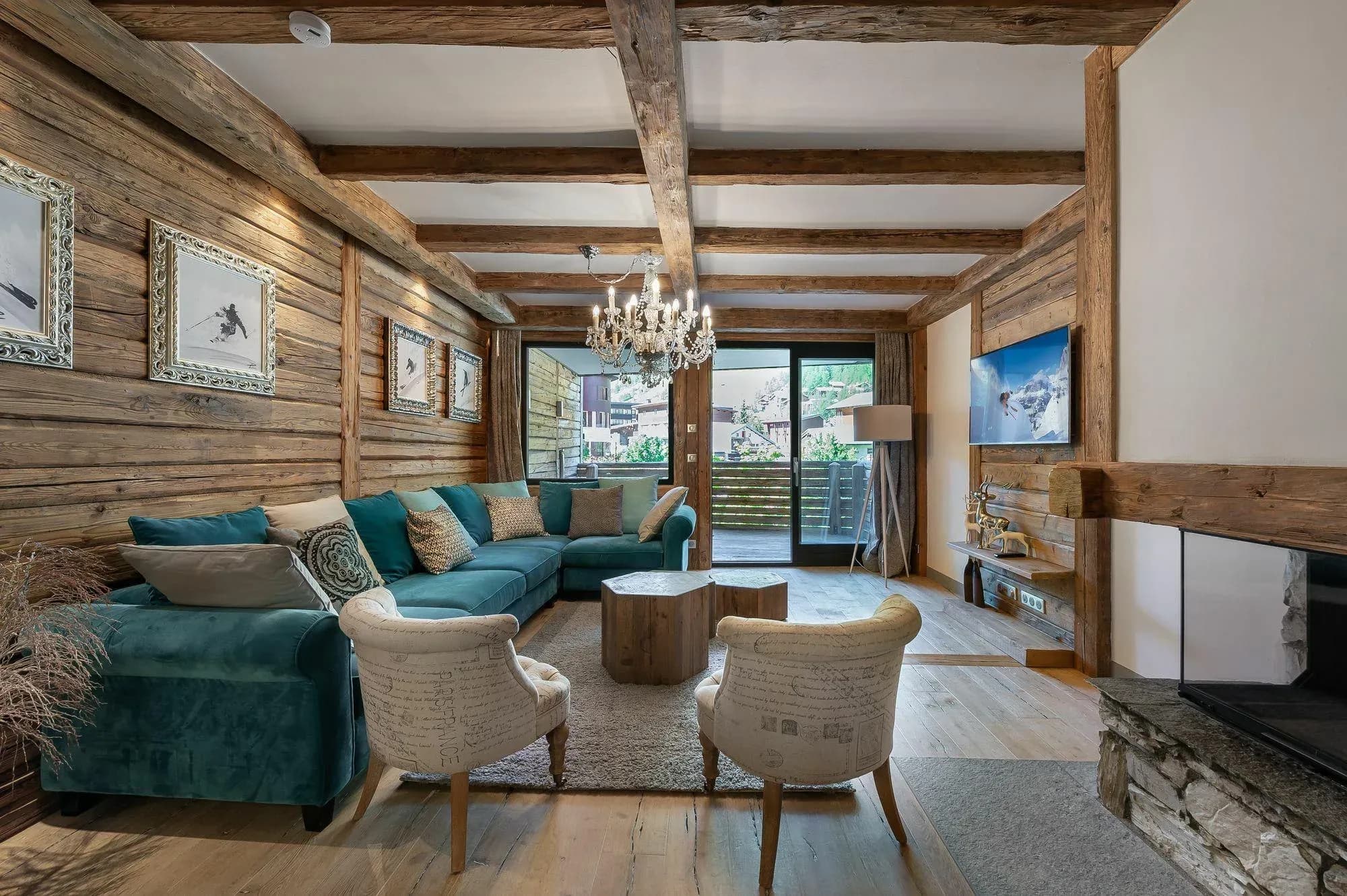 Living room with teal corner sofa, two armchairs, fireplace and balcony access
