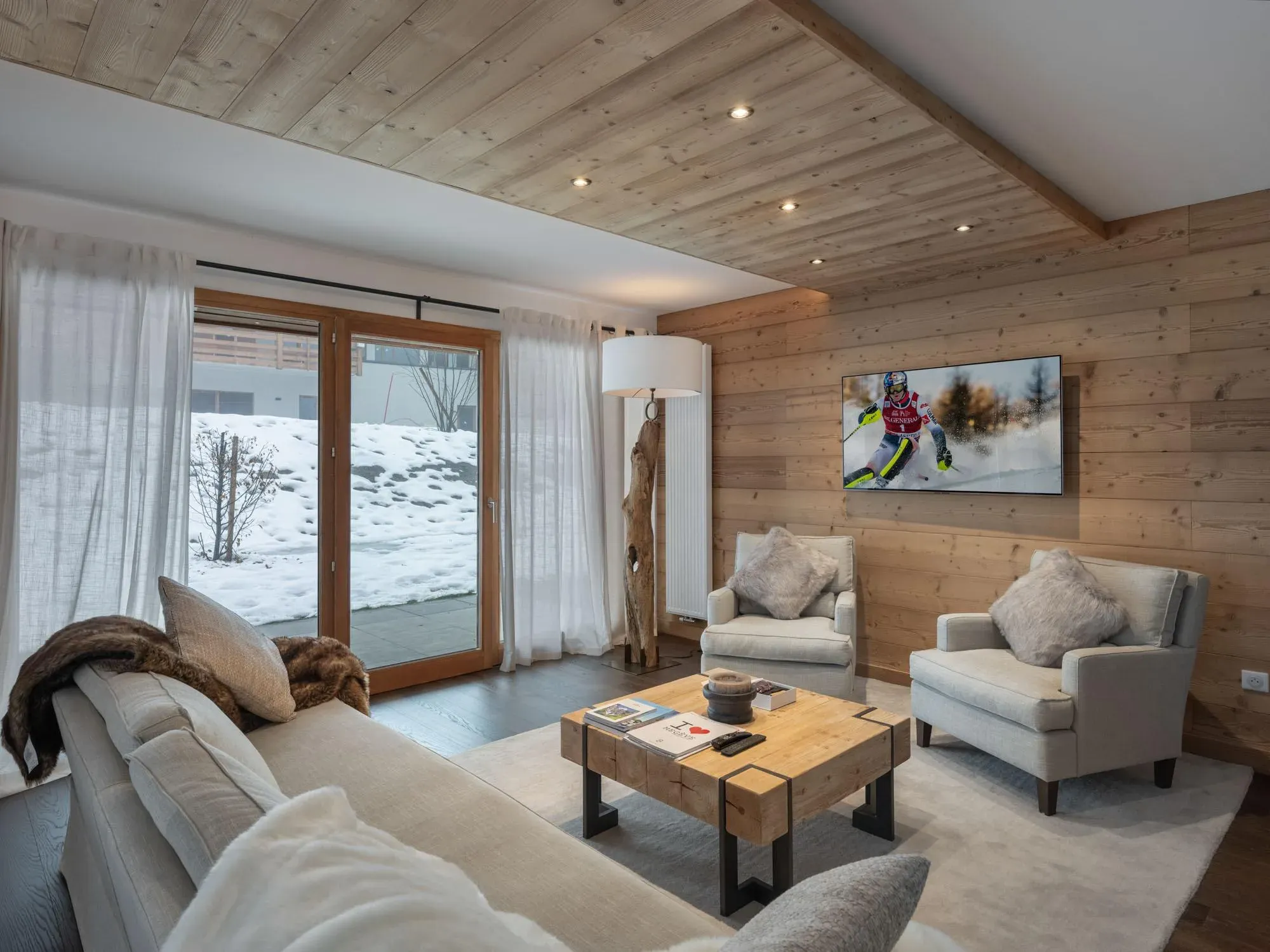 Living room with sofa, two armchairs, wall-mounted TV and sliding doors to the terrace