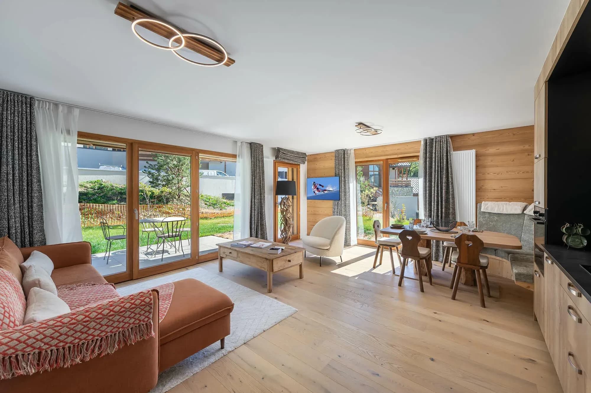 Open-plan living room with corner sofa, dining table and glass doors to terrace