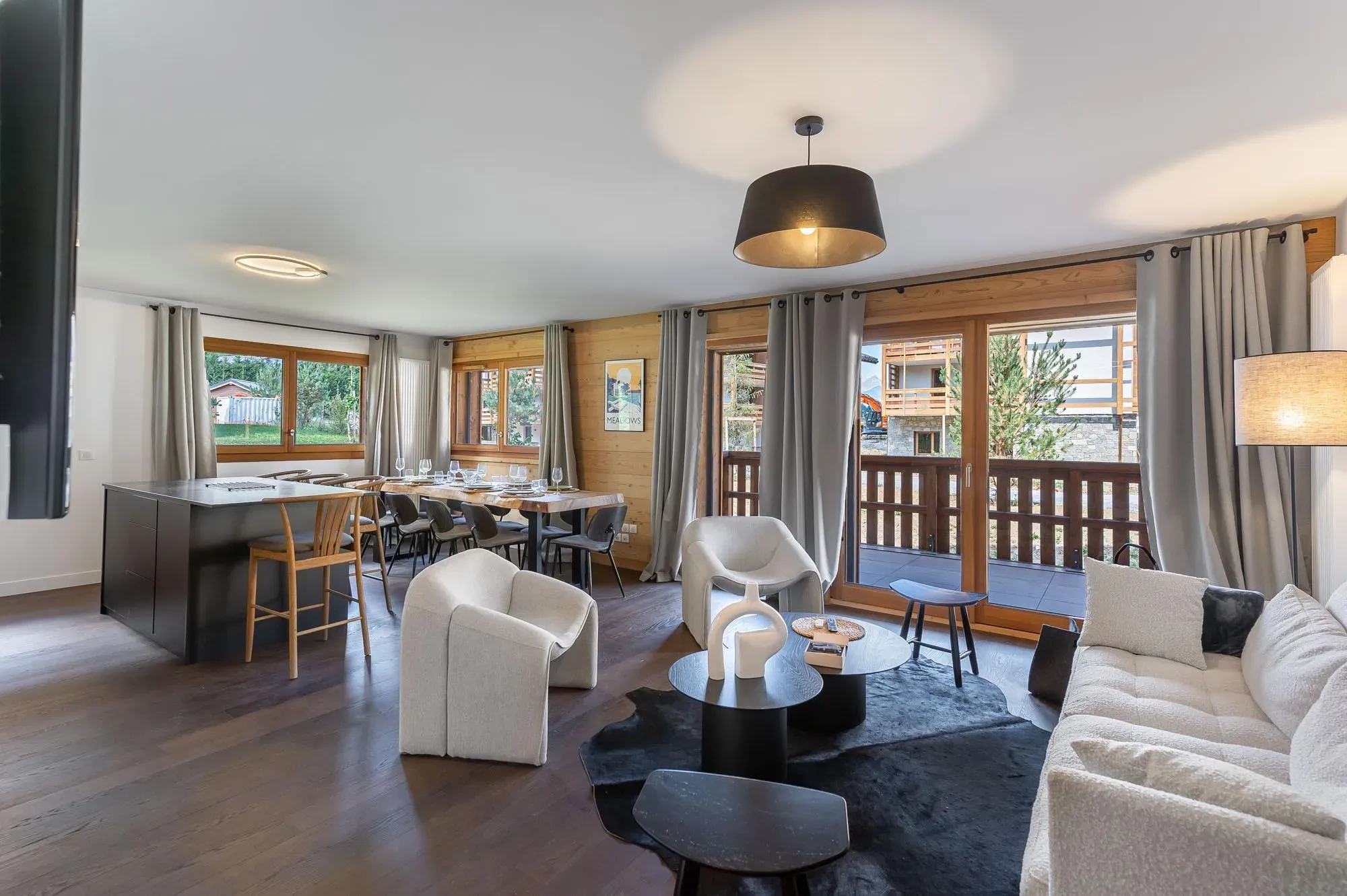 Open-plan lounge with white sofa, armchairs and glass doors to the balcony