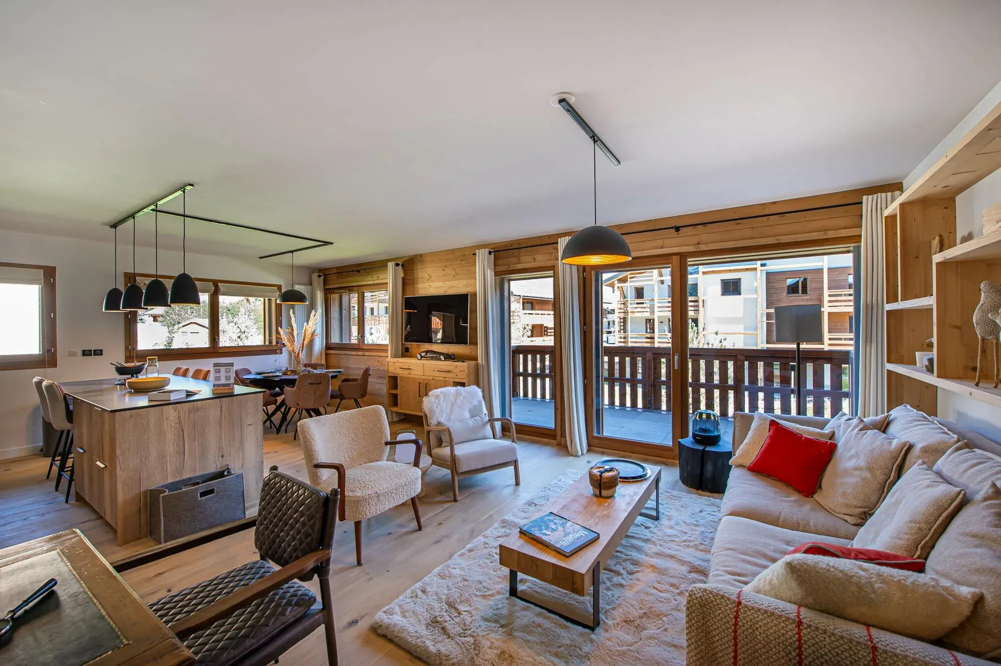 Open-plan lounge with corner sofa, armchairs, TV and balcony access