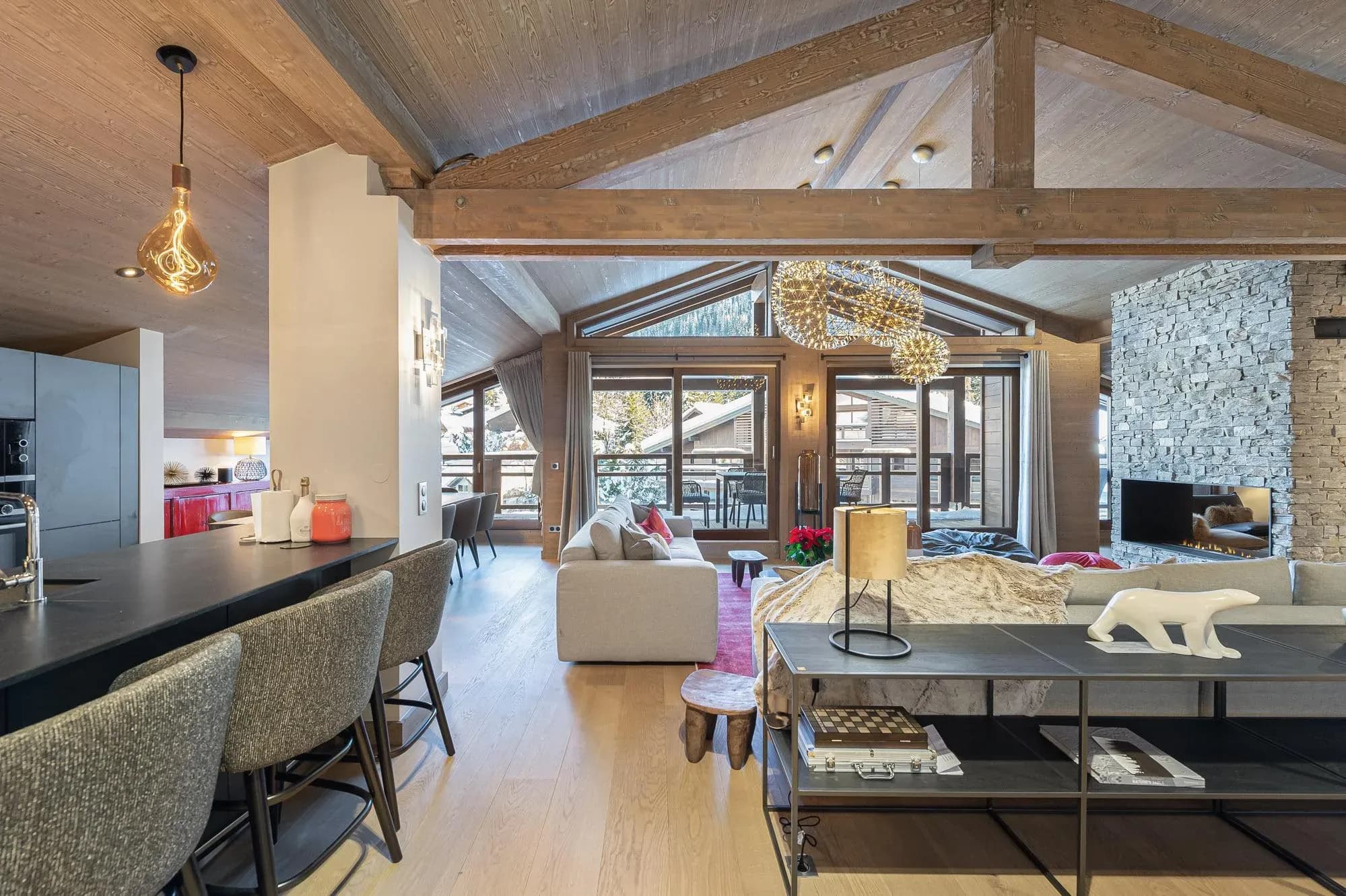 Open-plan living area with exposed beams, kitchen island bar stools and stone fireplace
