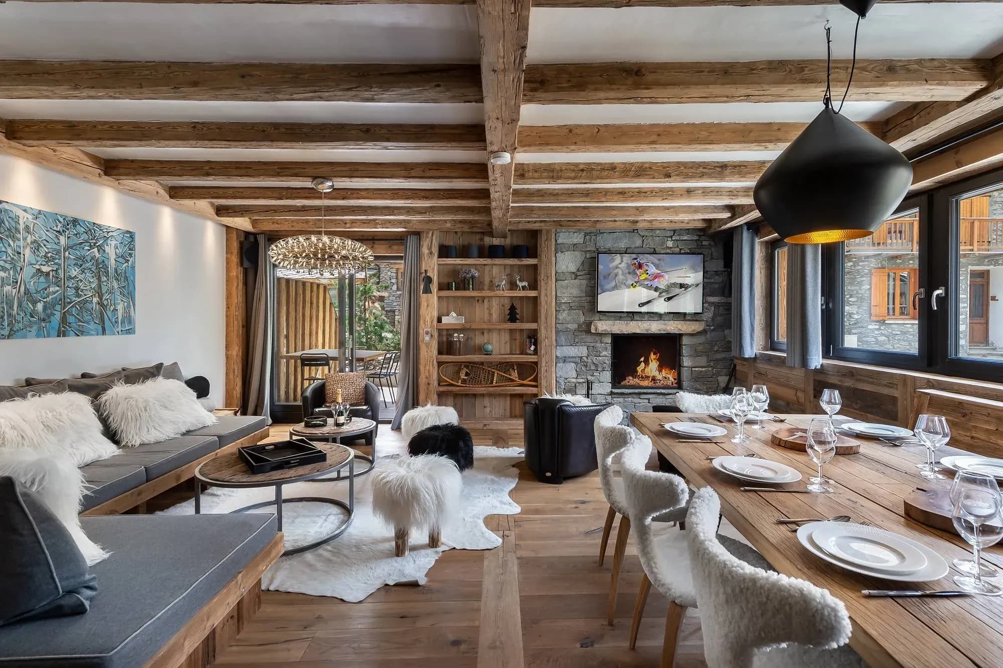 Open-plan lounge and dining area with stone fireplace, corner sofa and long wooden table