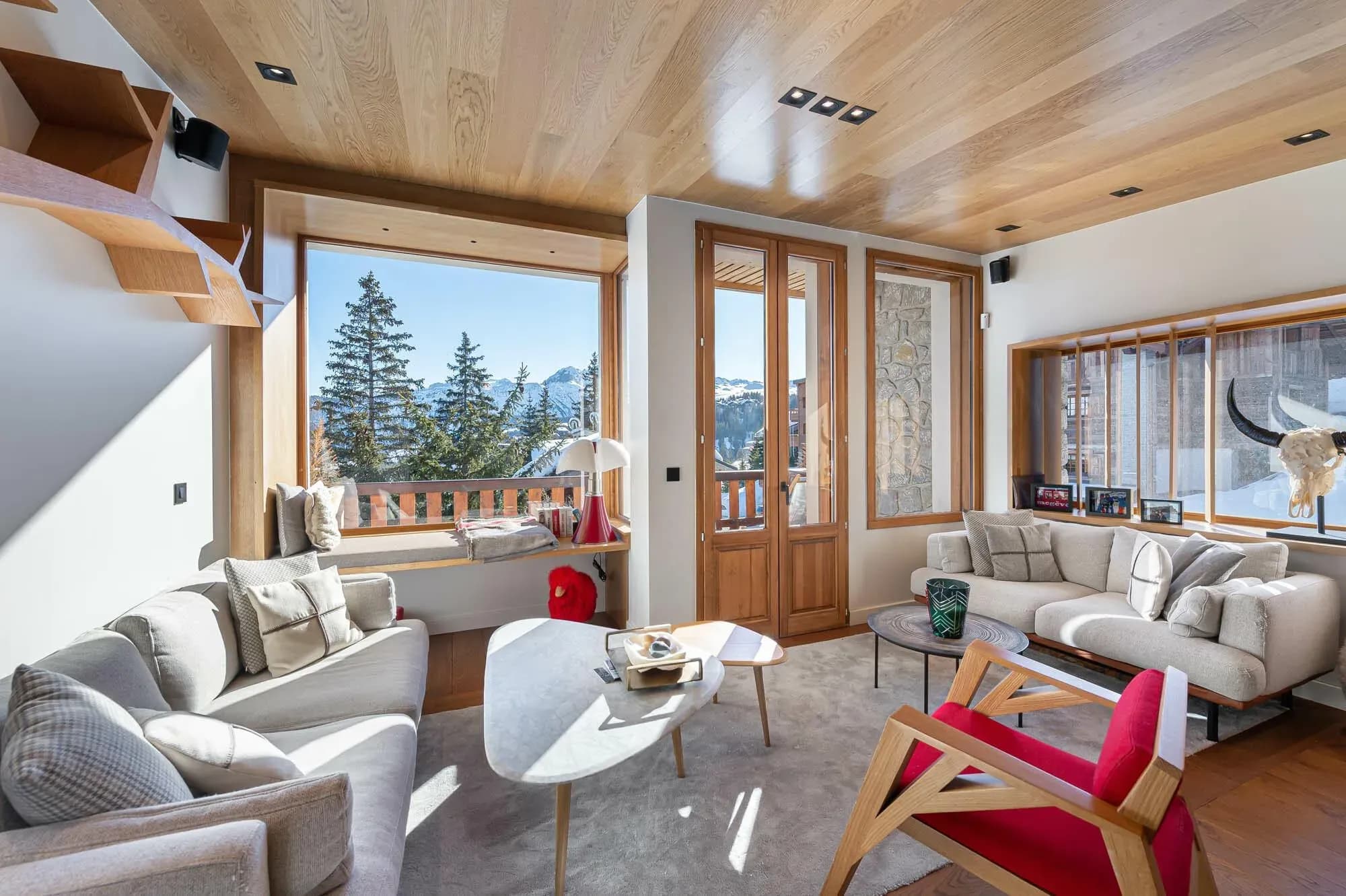 Living room with two sofas, window seat and mountain views through French doors