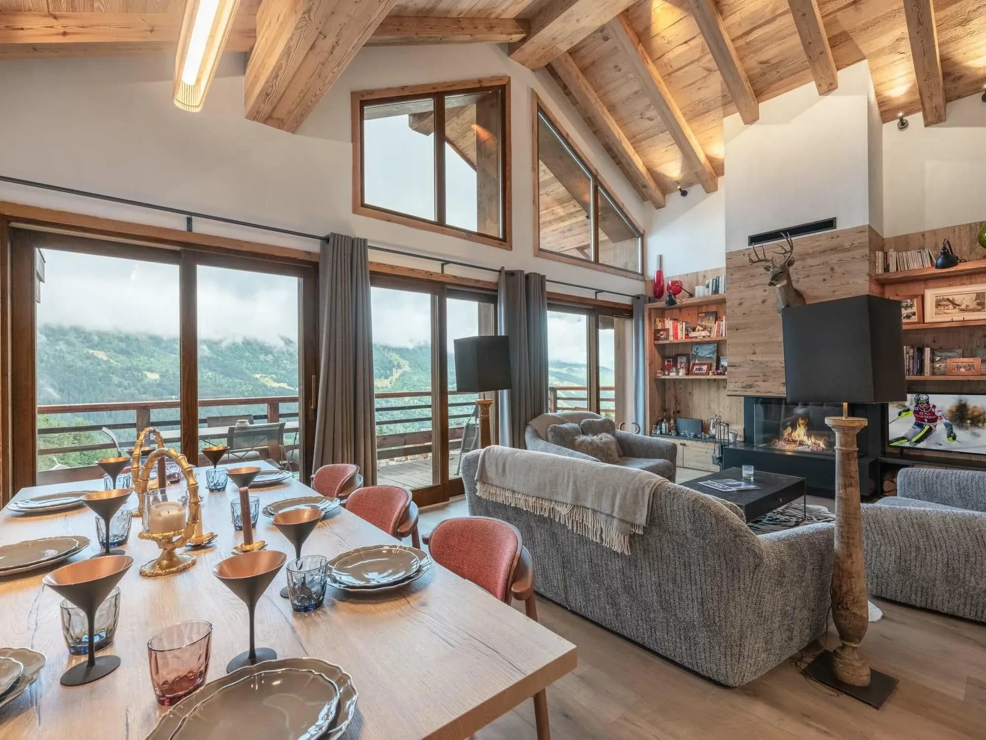 Lounge with grey sofas, wood-burning fireplace and floor-to-ceiling mountain-view windows