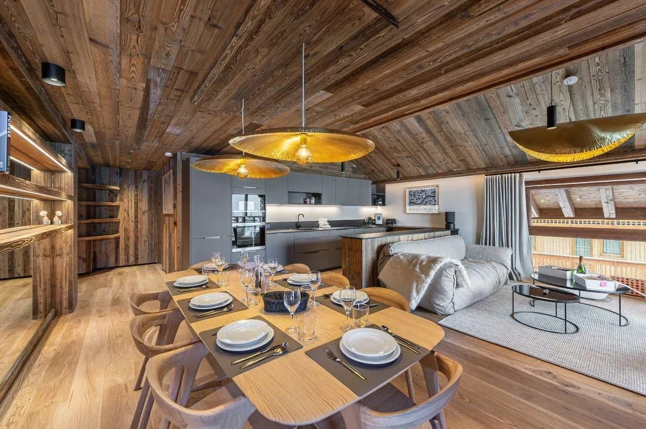 Dining table for eight under gold pendant lights, open kitchen and lounge behind