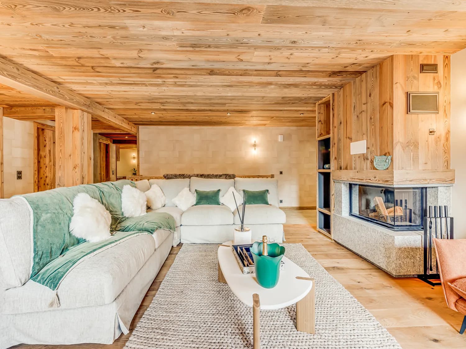 Open-plan lounge with a corner fireplace, timber ceiling and sofa