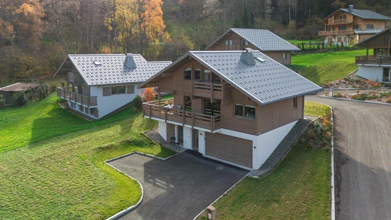 Chalet exterior with wooden balconies, garage and gravel driveway