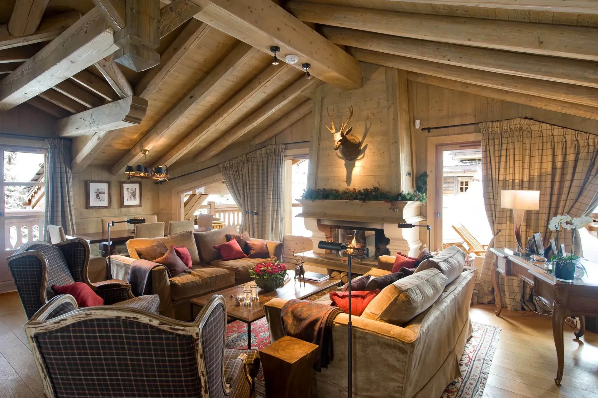 Living room with stone fireplace, two sofas, tartan armchairs and dining table behind