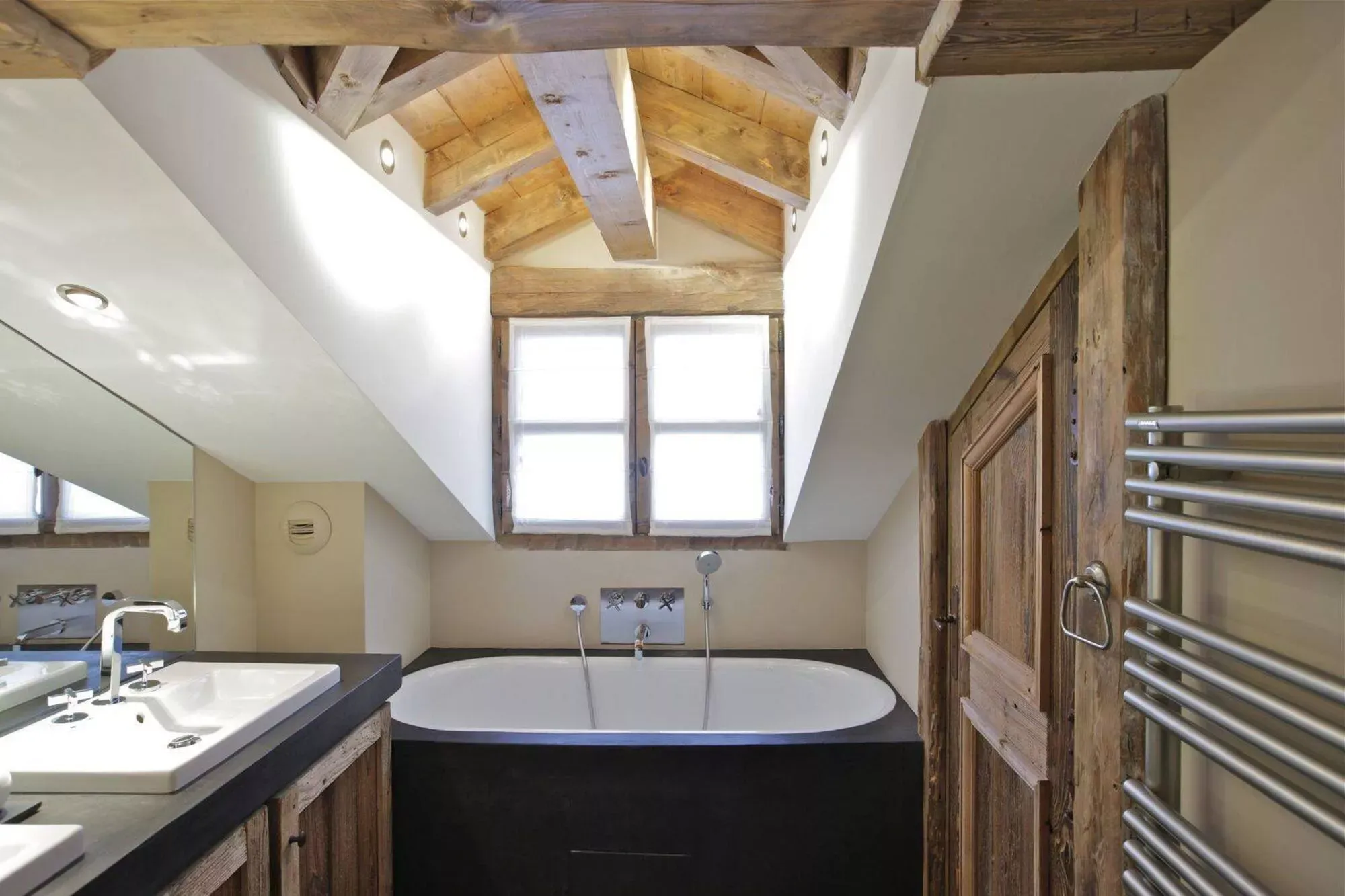 Top-floor bathroom with bath beneath exposed timber beams
