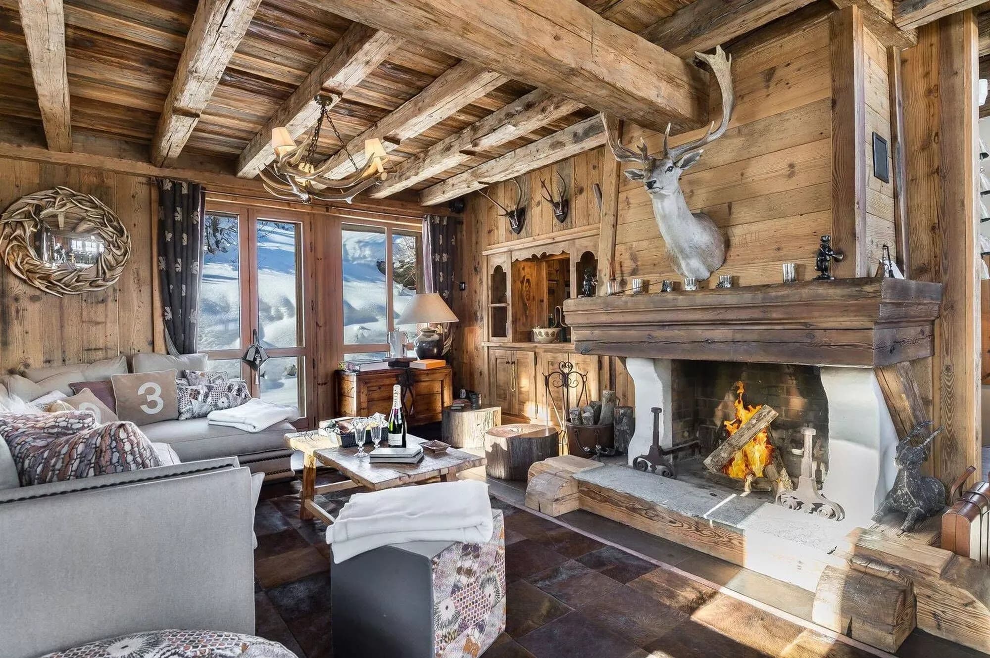 Living room with a stone fireplace, timber ceiling and mountain-facing windows