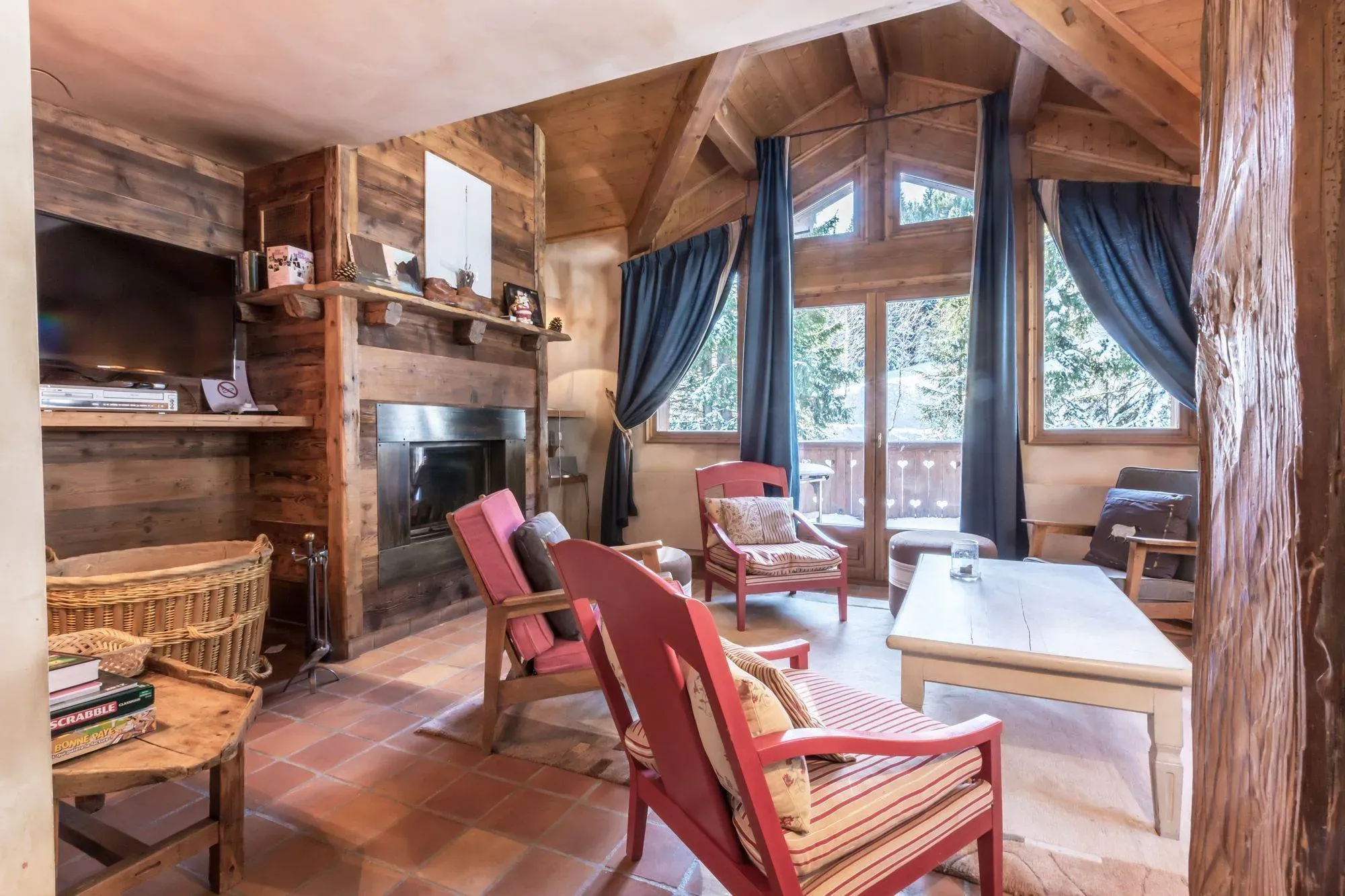 Living room with wood-framed fireplace, red armchairs and balcony doors