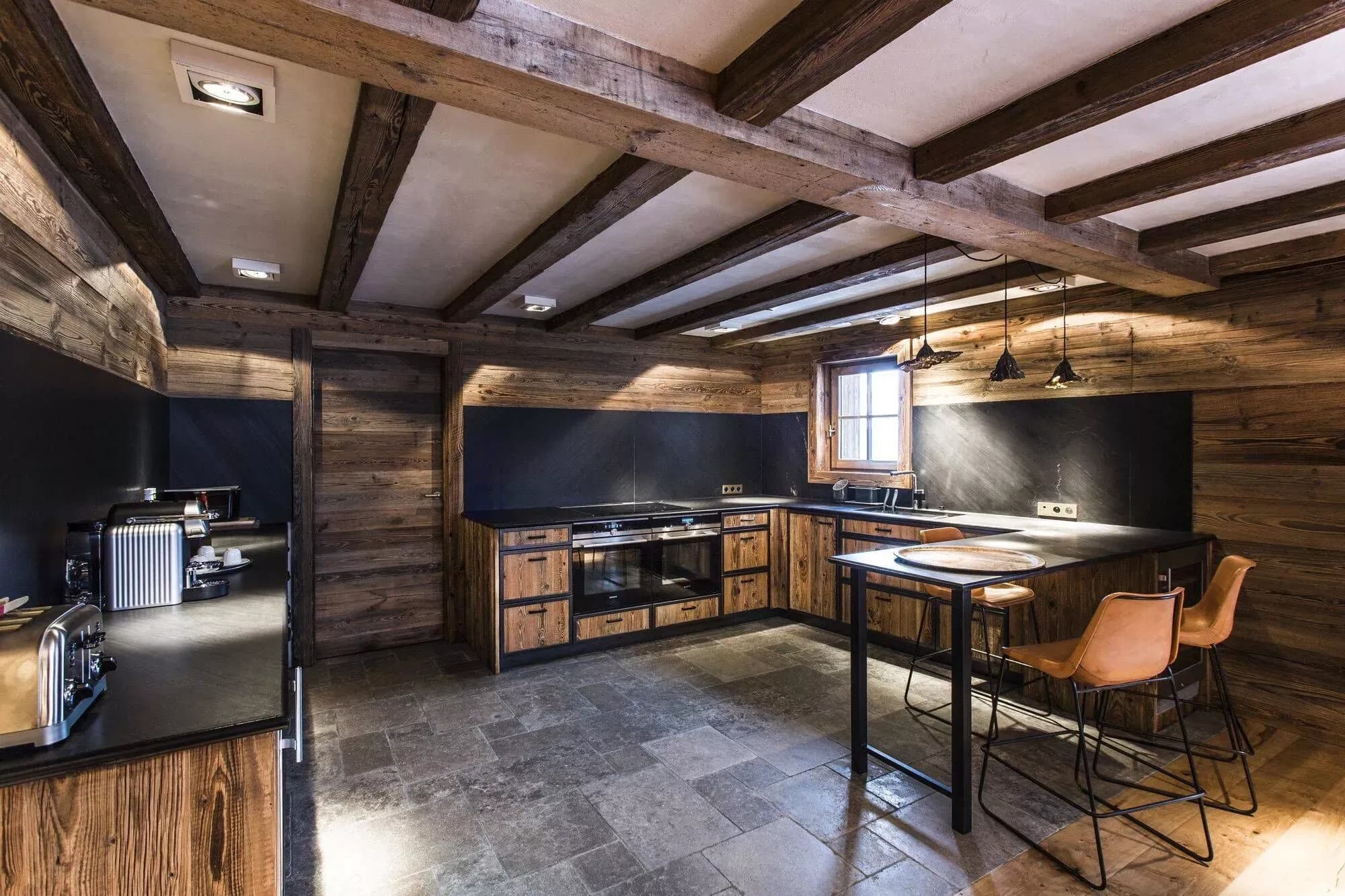 Open kitchen with black cabinetry, stone flooring and a breakfast bar