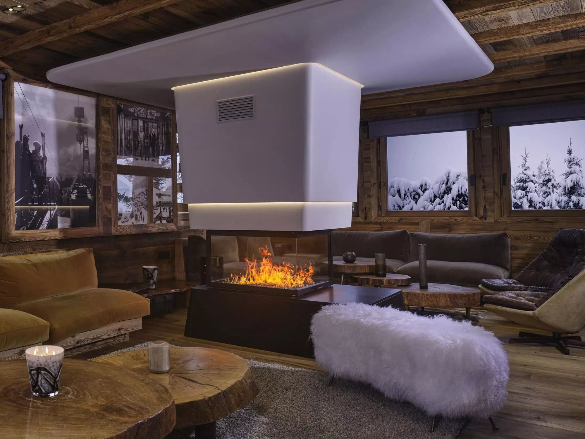 Timber-lined lounge with central fireplace and snowy views