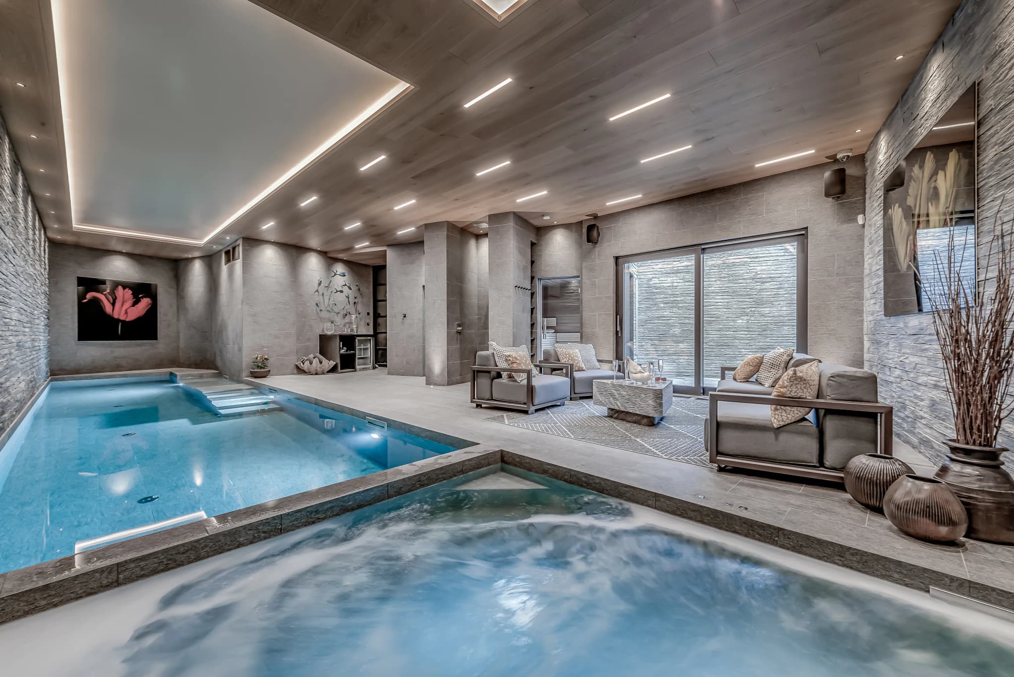 Indoor swimming pool with a sunken hot tub and poolside loungers