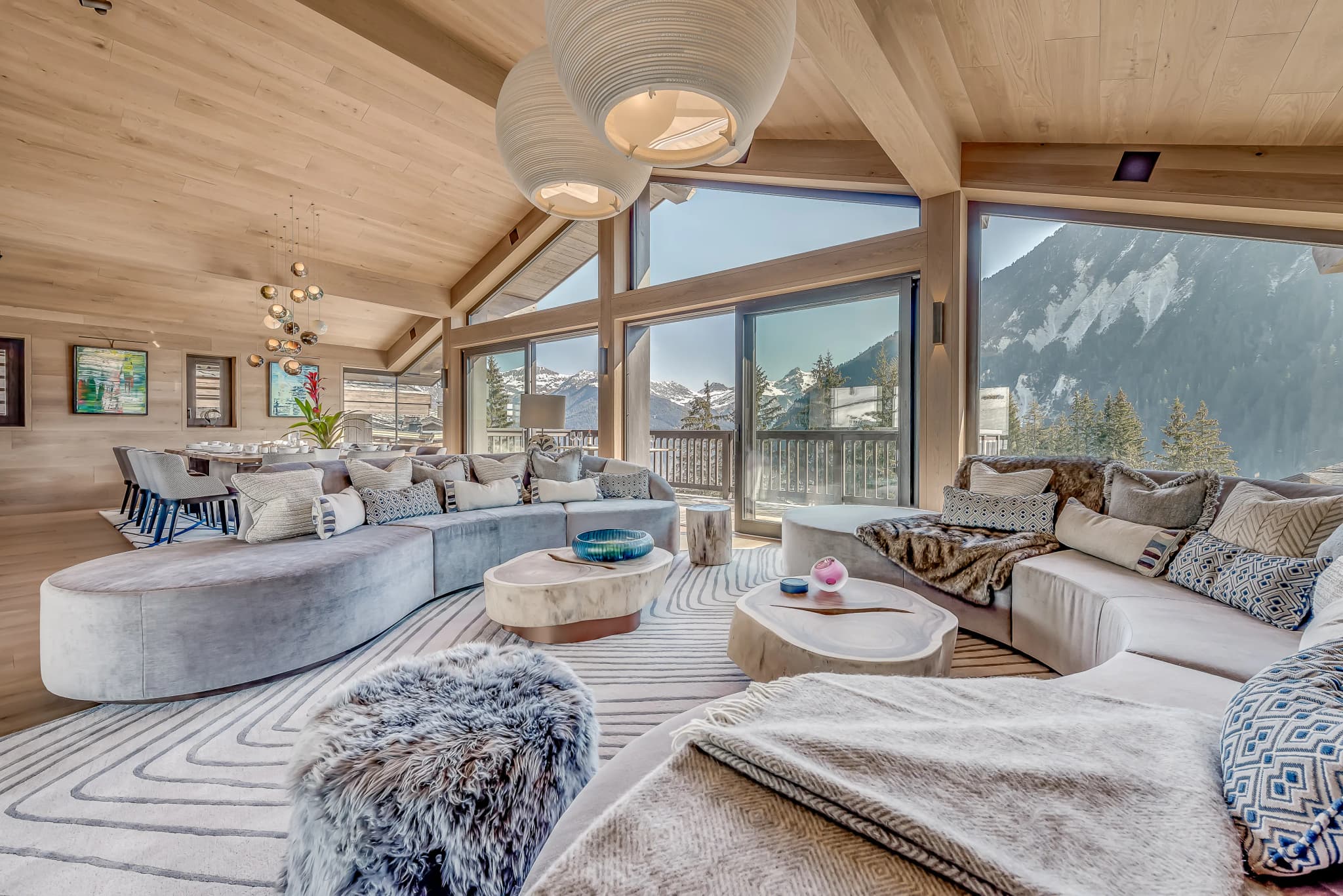 Double-height lounge with a fireplace and panoramic mountain windows