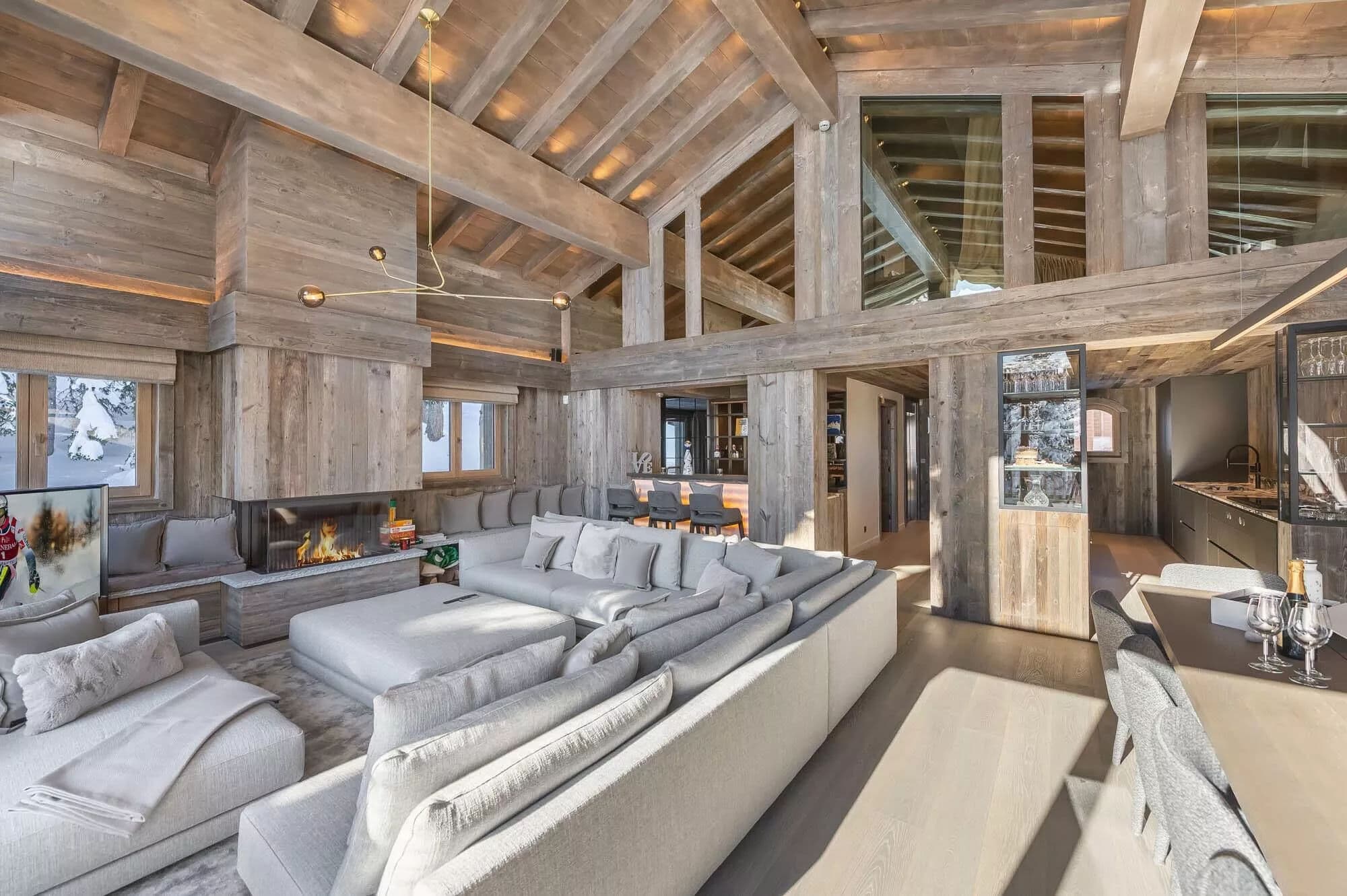 Double-height living room with pale sectional seating and exposed timber beams