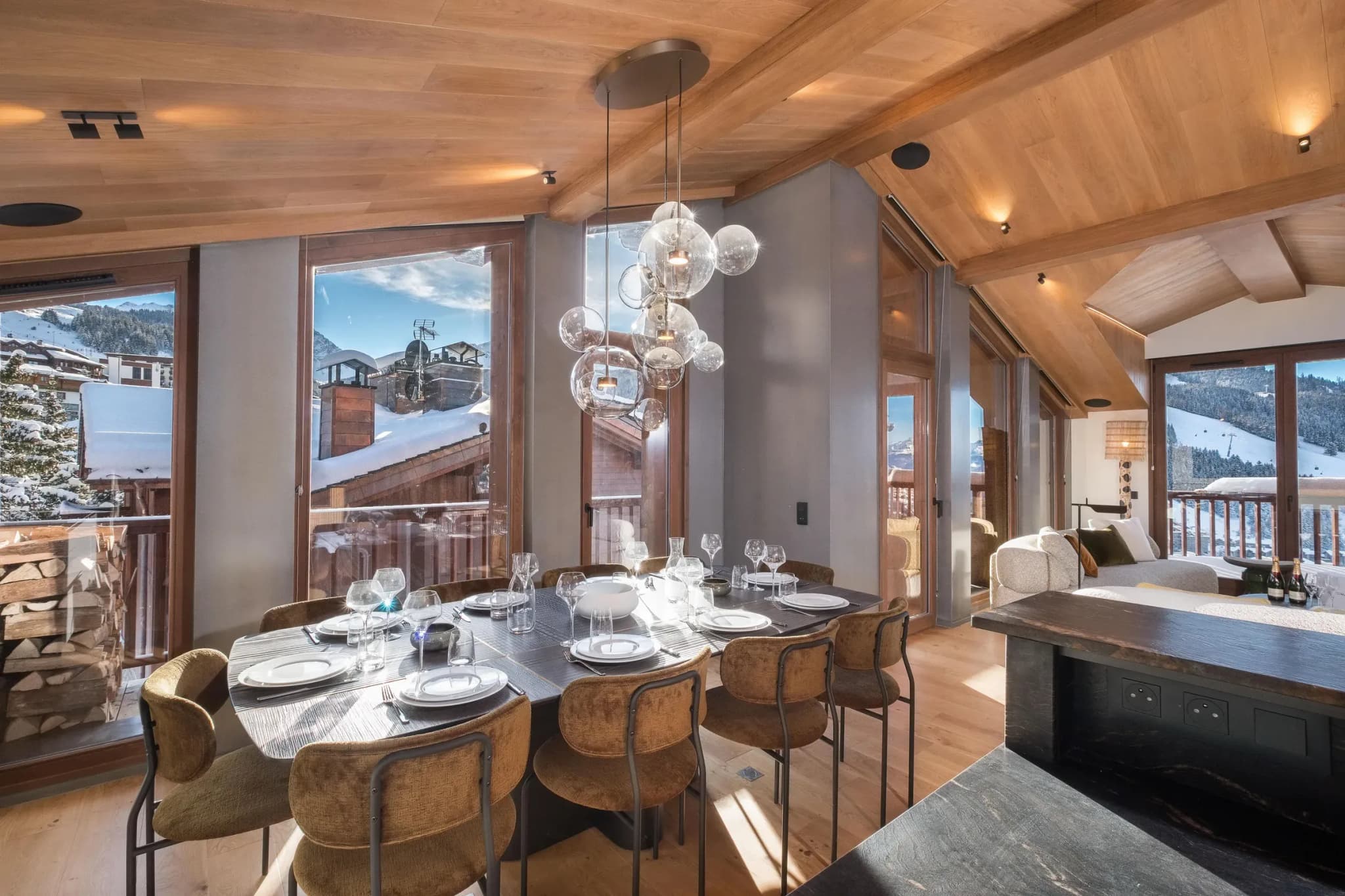 Dining table with eight chairs and glass pendant lights beside balcony windows