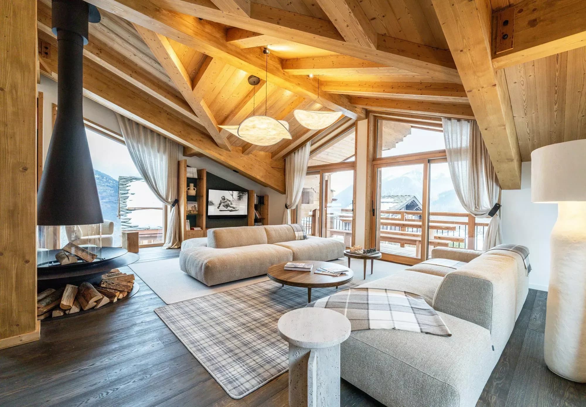Lounge with central suspended fireplace, balcony doors and mountain views