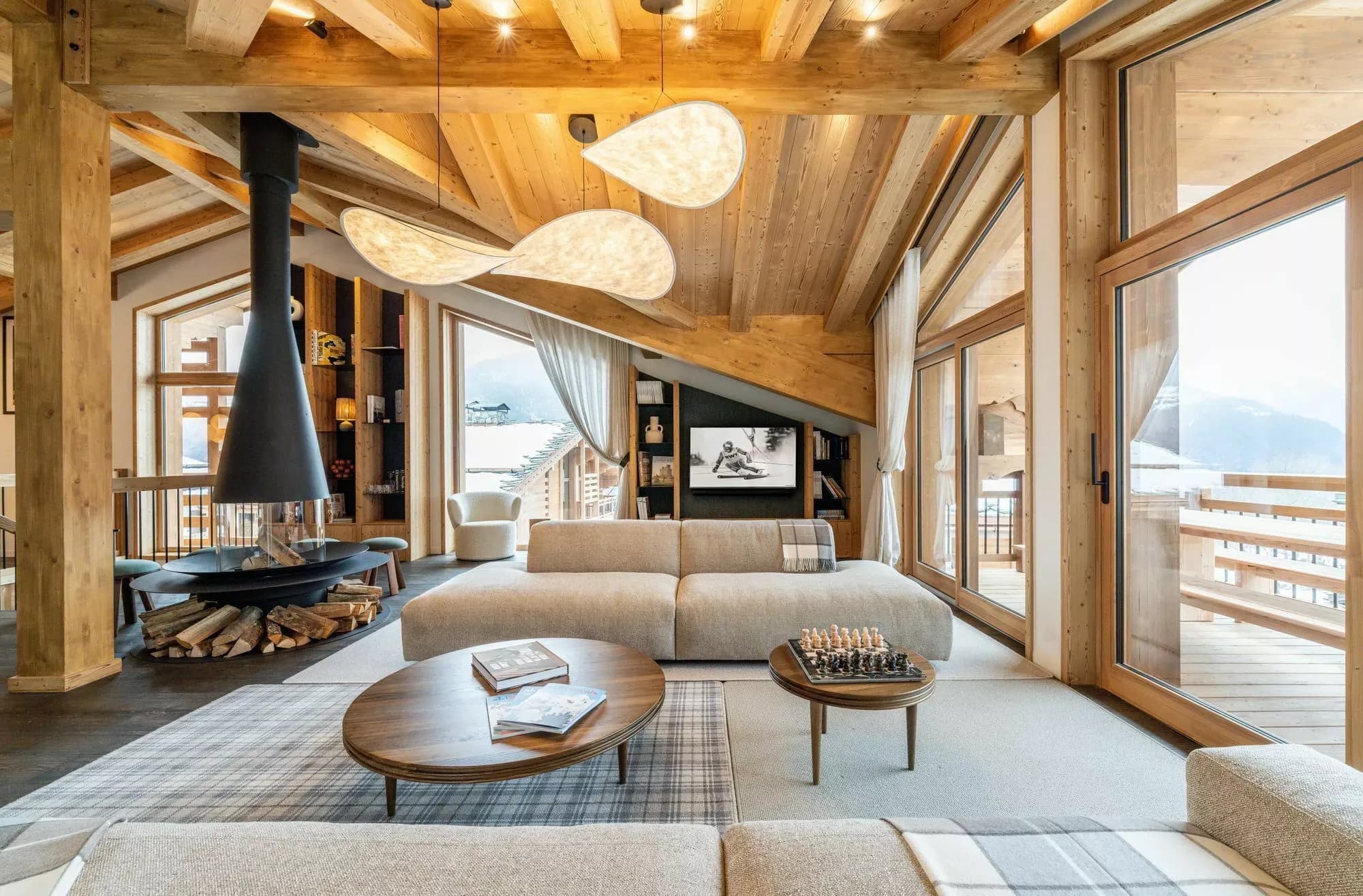 Lounge seating around the central wood fireplace with terrace and mountain views