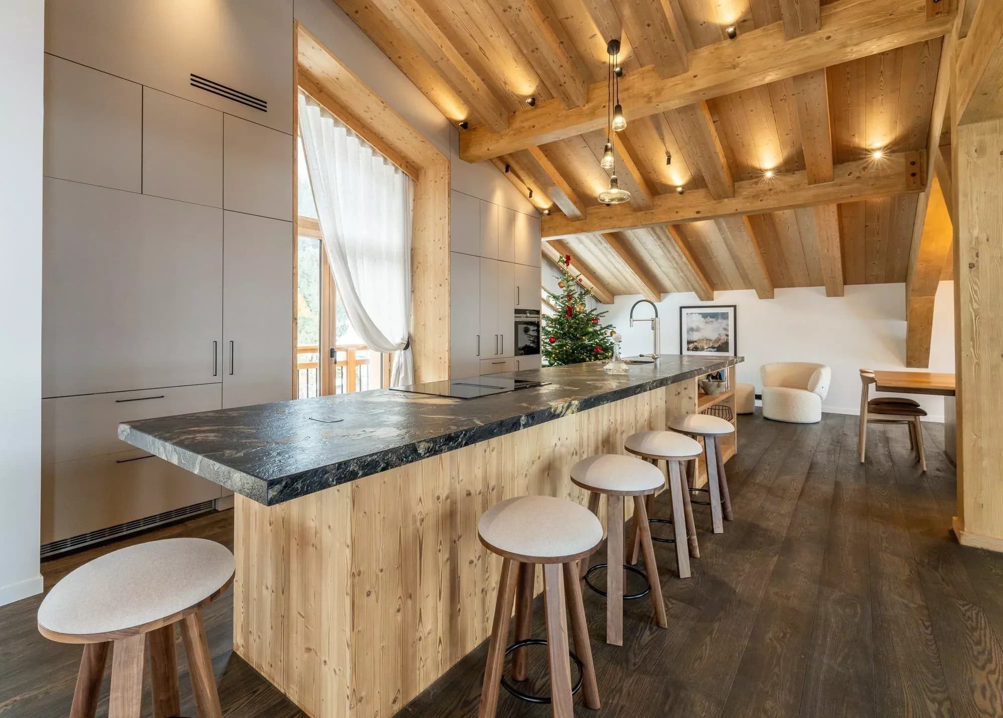 Open kitchen with stone island, breakfast stools and timber ceiling