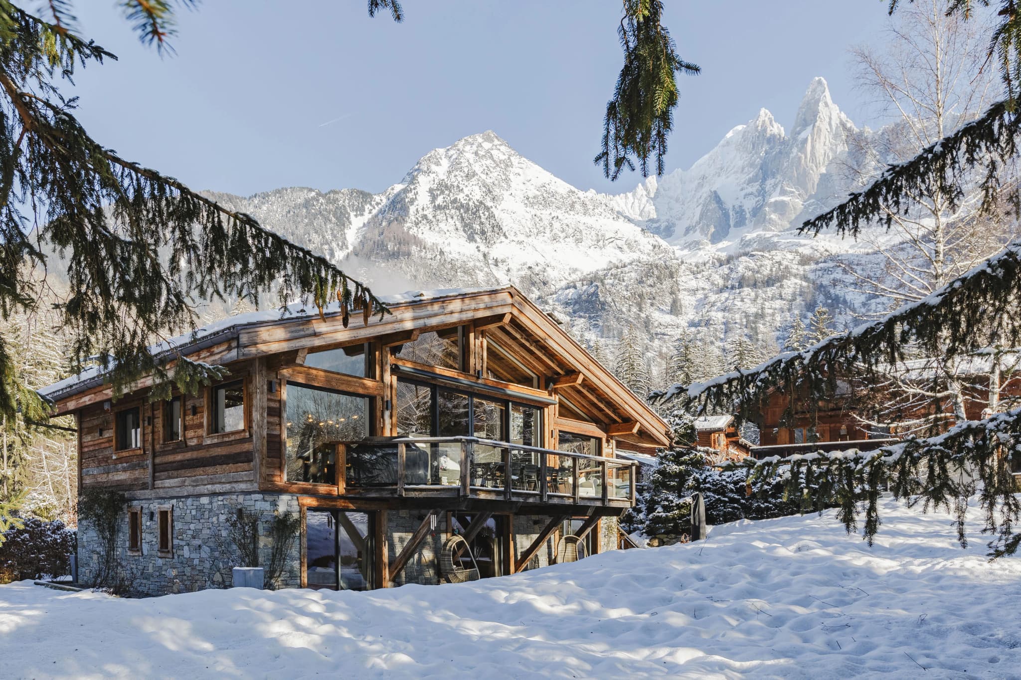 Snow-covered timber chalet framed by trees and a mountain backdrop