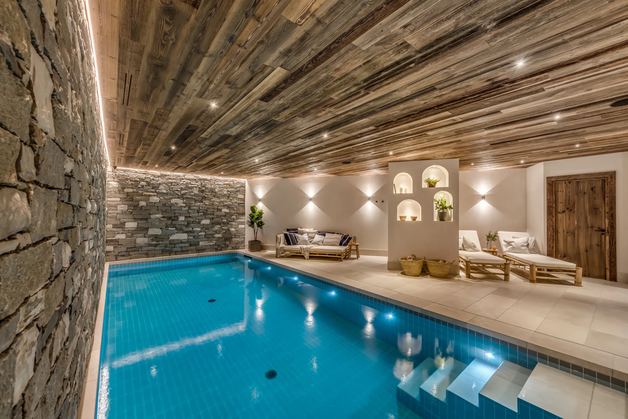 Indoor swimming pool with stone walls and loungers