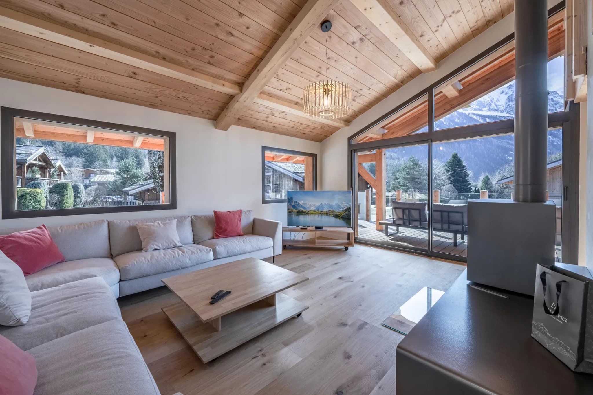 Living room with corner sofa, wood stove and glazed doors to the terrace