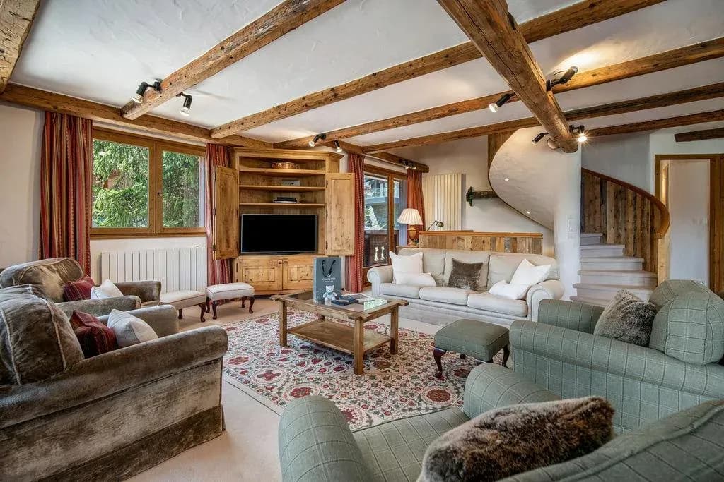 Living area with wood-beam ceilings, TV cabinet, and spiral staircase access