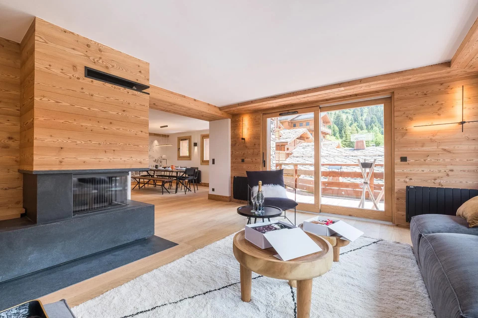 Living room with double-sided fireplace, grey sofa and balcony doors