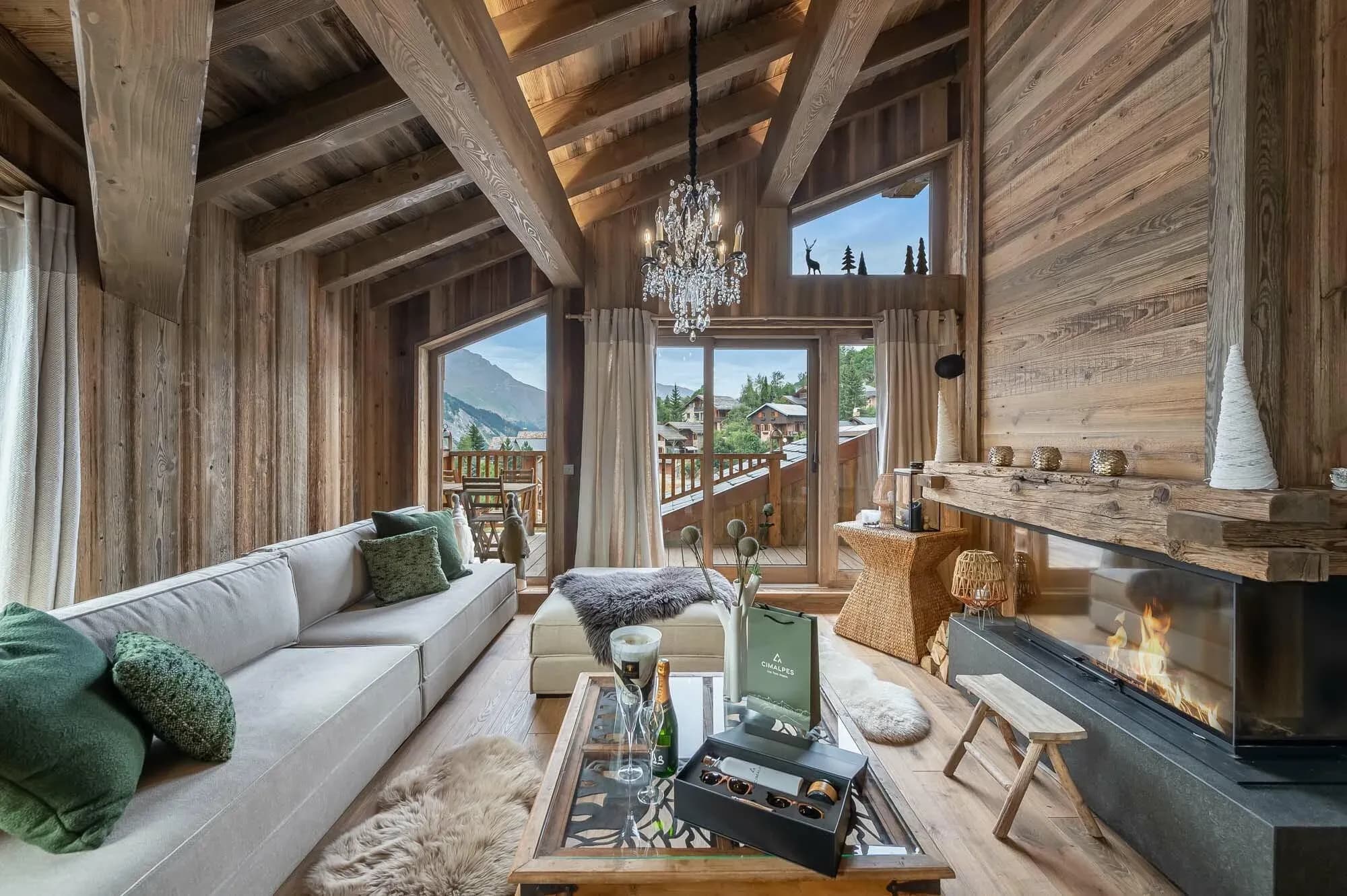 Living room with corner wood fireplace, grey sofa and balcony doors to mountain view