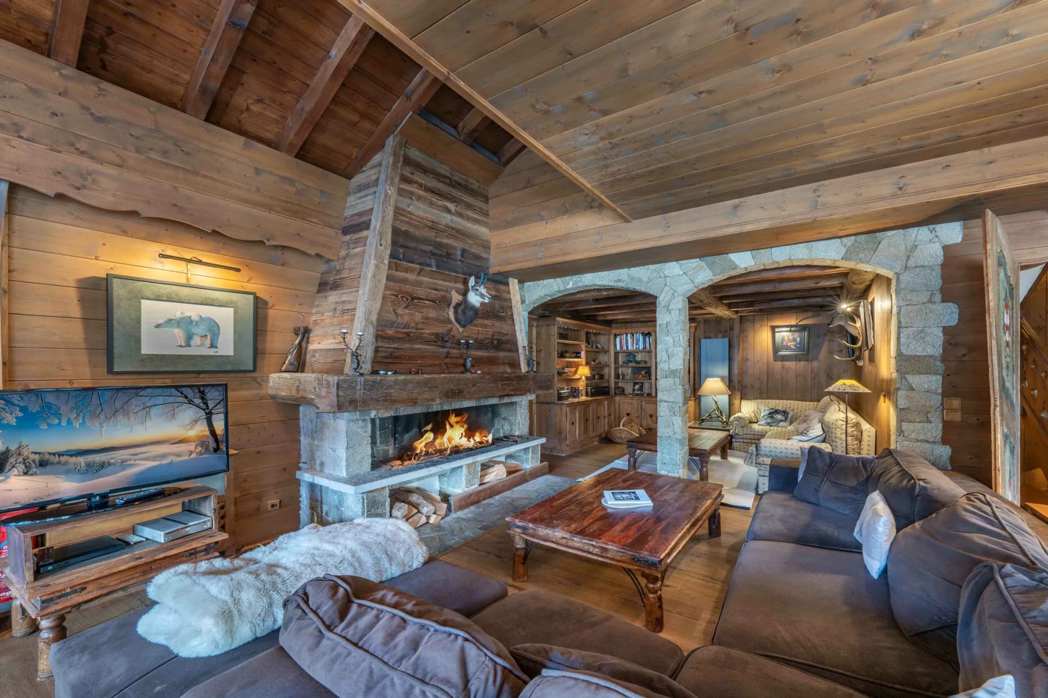Living room with stone fireplace, corner sofa and wall-mounted TV