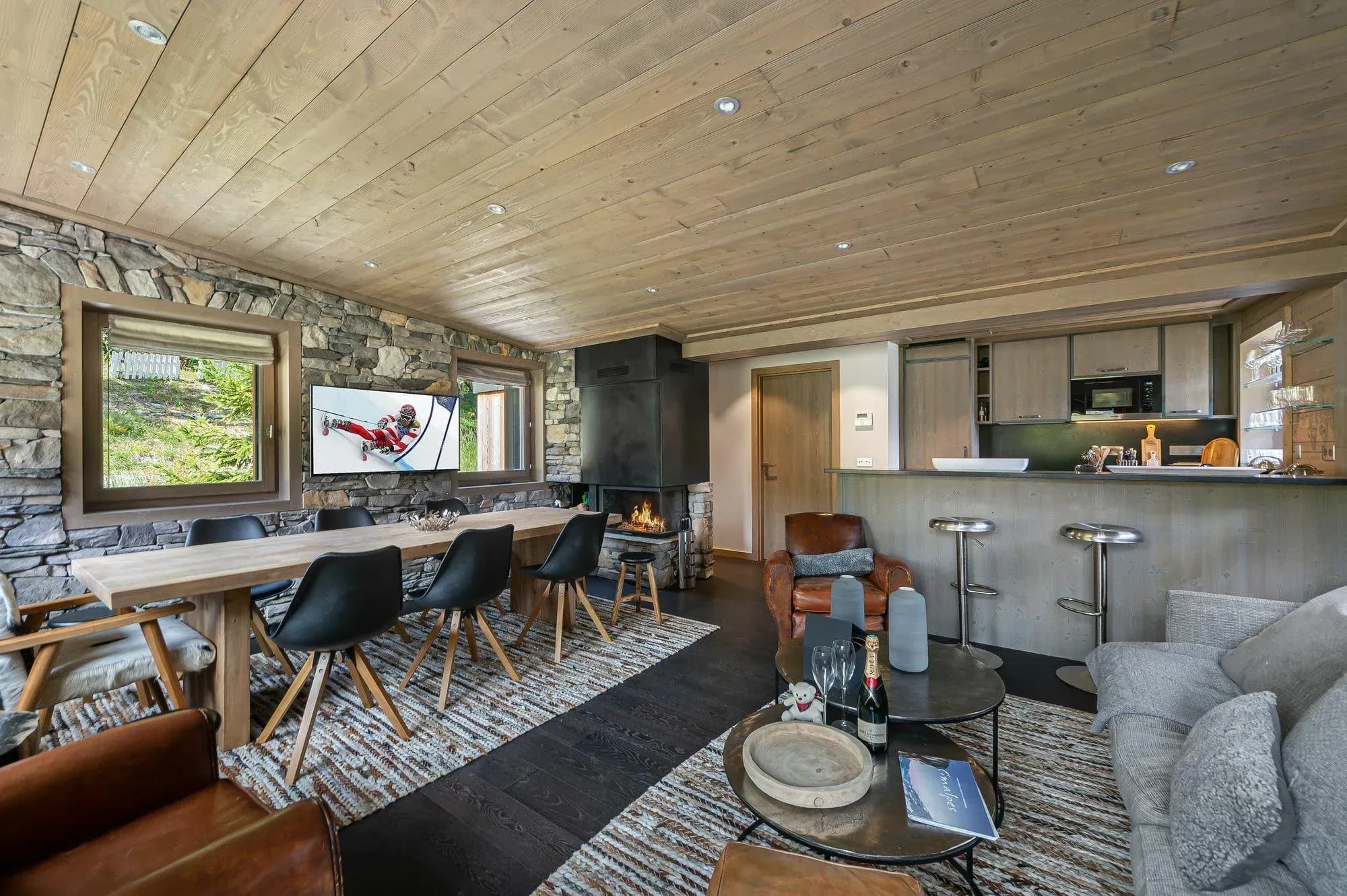 Open-plan lounge with wood fireplace, grey sofa, dining table and breakfast bar