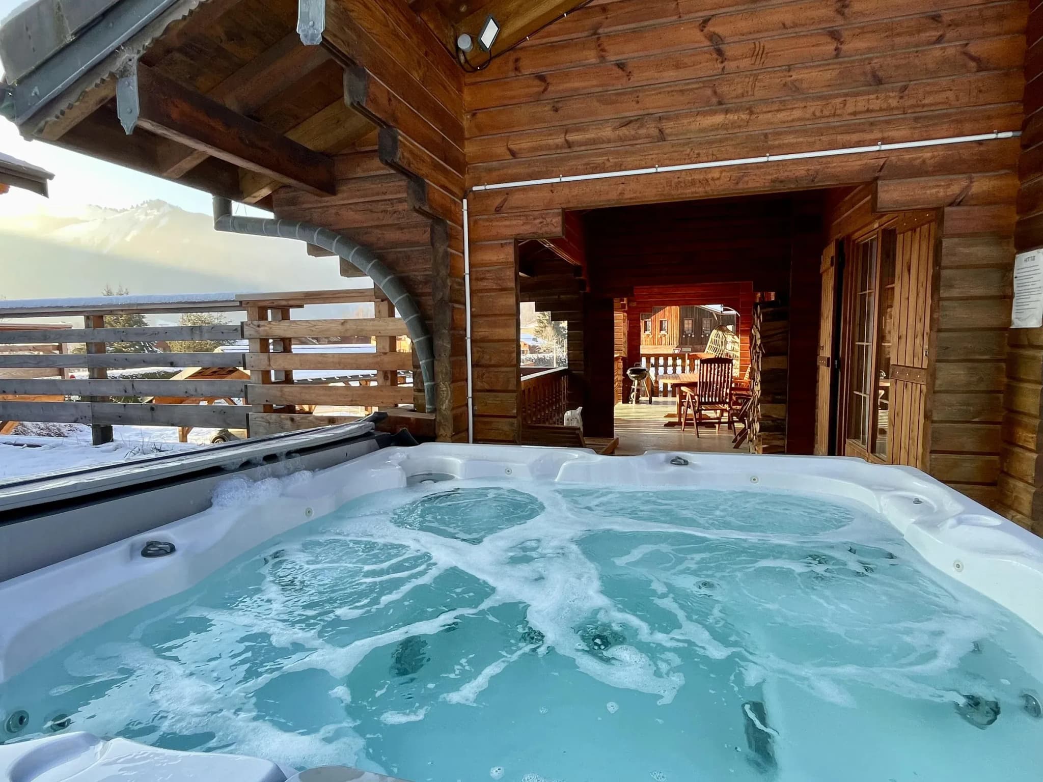 Outdoor hot tub beside the covered terrace, with mountain views