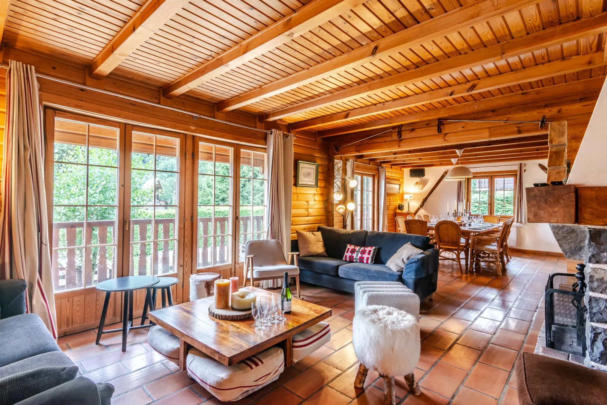 Living room with blue sofa, low wooden table and balcony doors; dining table beyond
