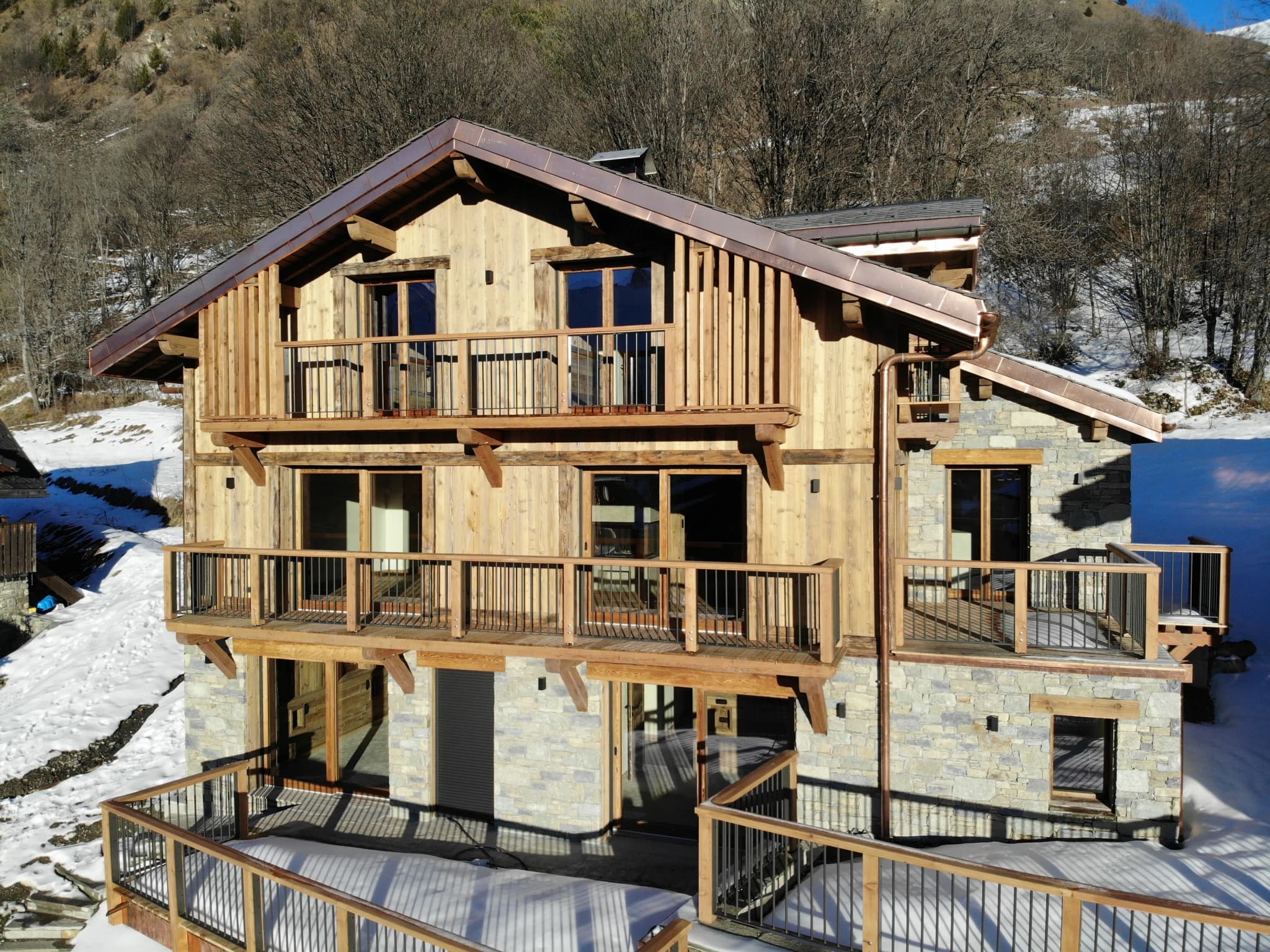 Chalet Corbeau in winter with its timber balconies and stone ground floor