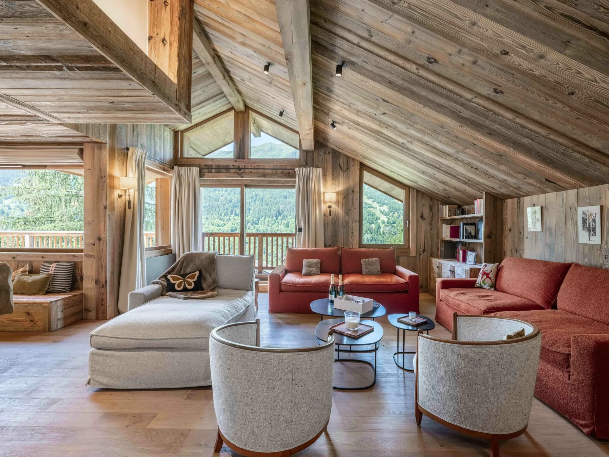 Living room with orange sofas, chaise longue and mountain views through tall windows