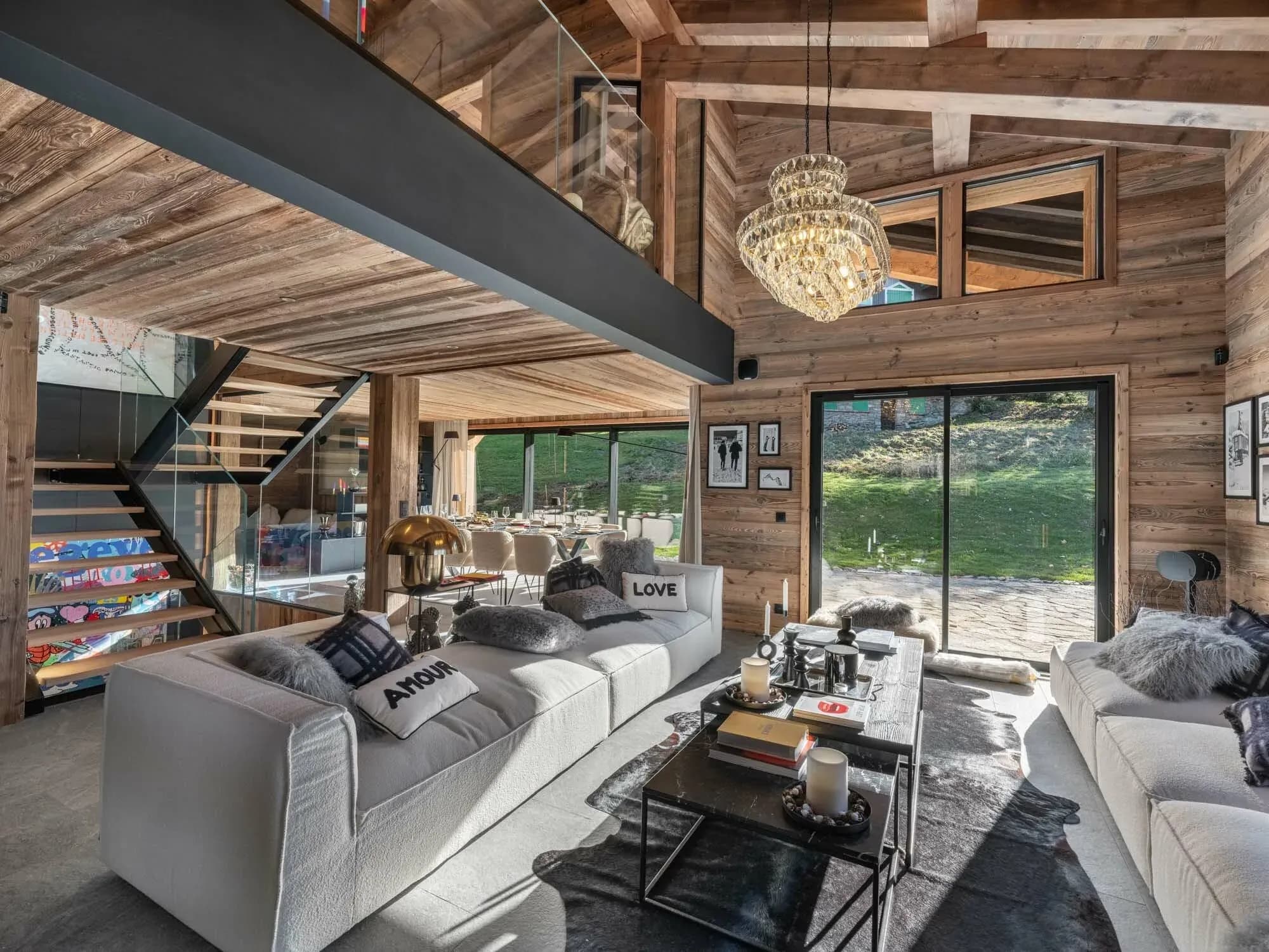 Living room with two white sofas, crystal chandelier and glass doors to the garden