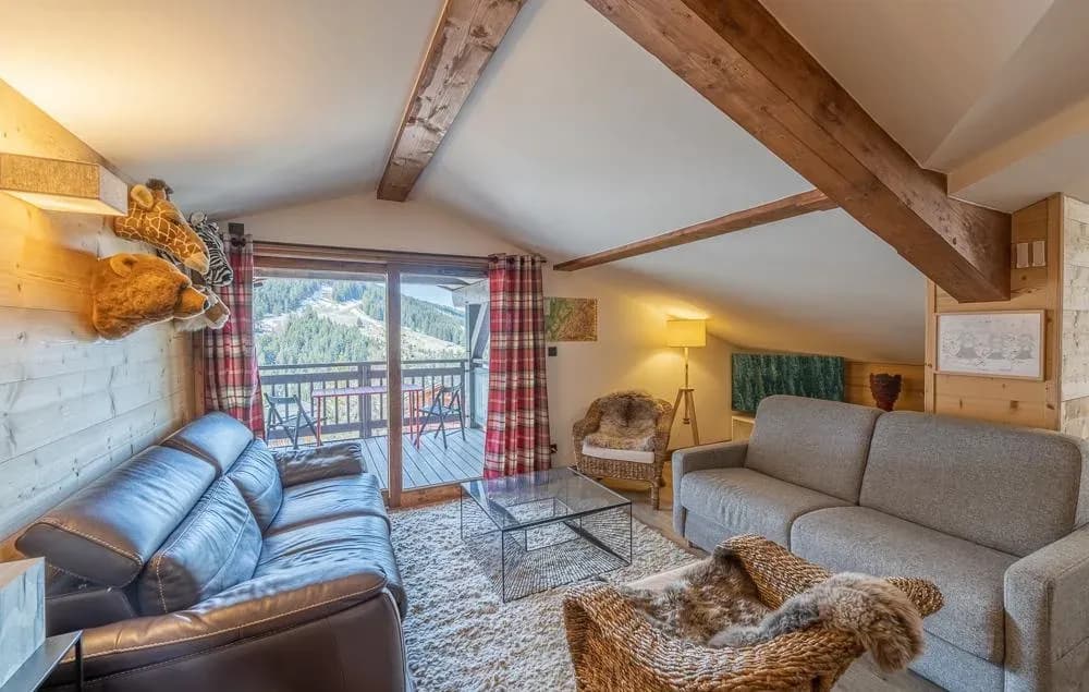 Lounge with leather sofa, grey sofa bed and balcony door facing the slopes