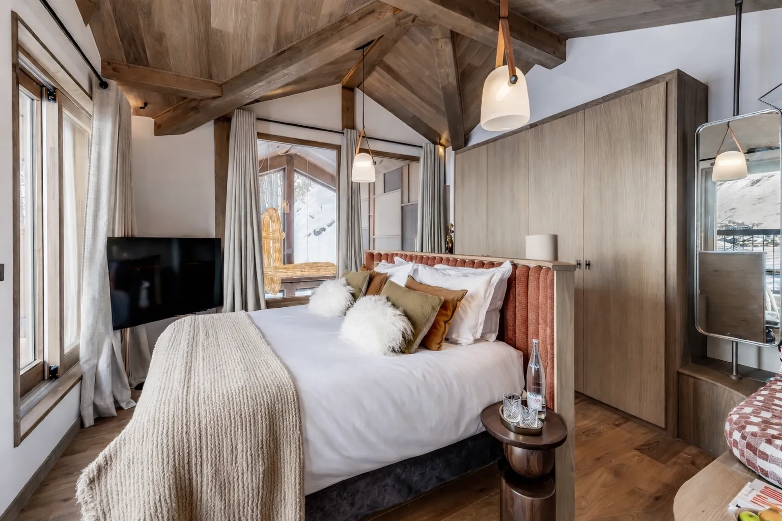 Primary bedroom under exposed beams with balcony doors