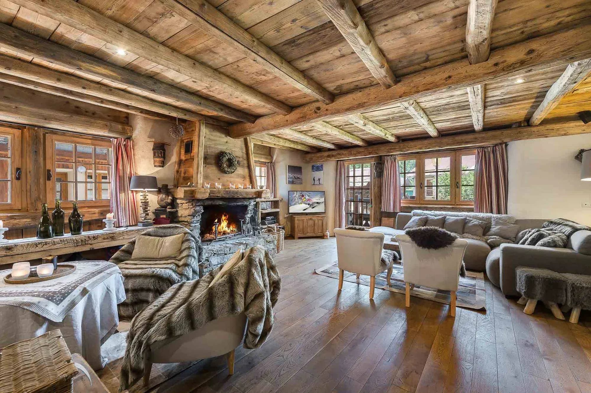 Living room with stone fireplace, corner sofa and armchairs on wide plank floor