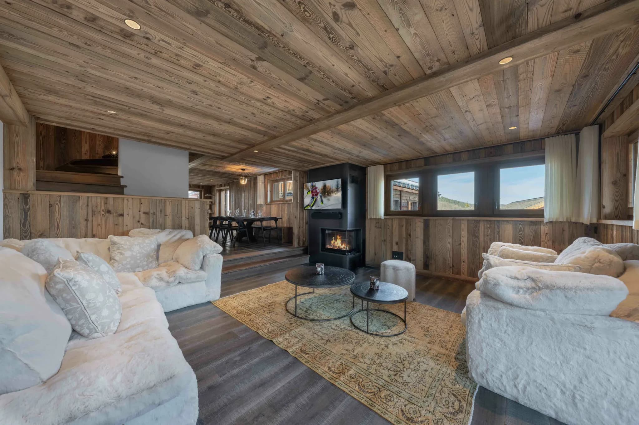 Lounge with corner fireplace, two white sofas and view of the dining area