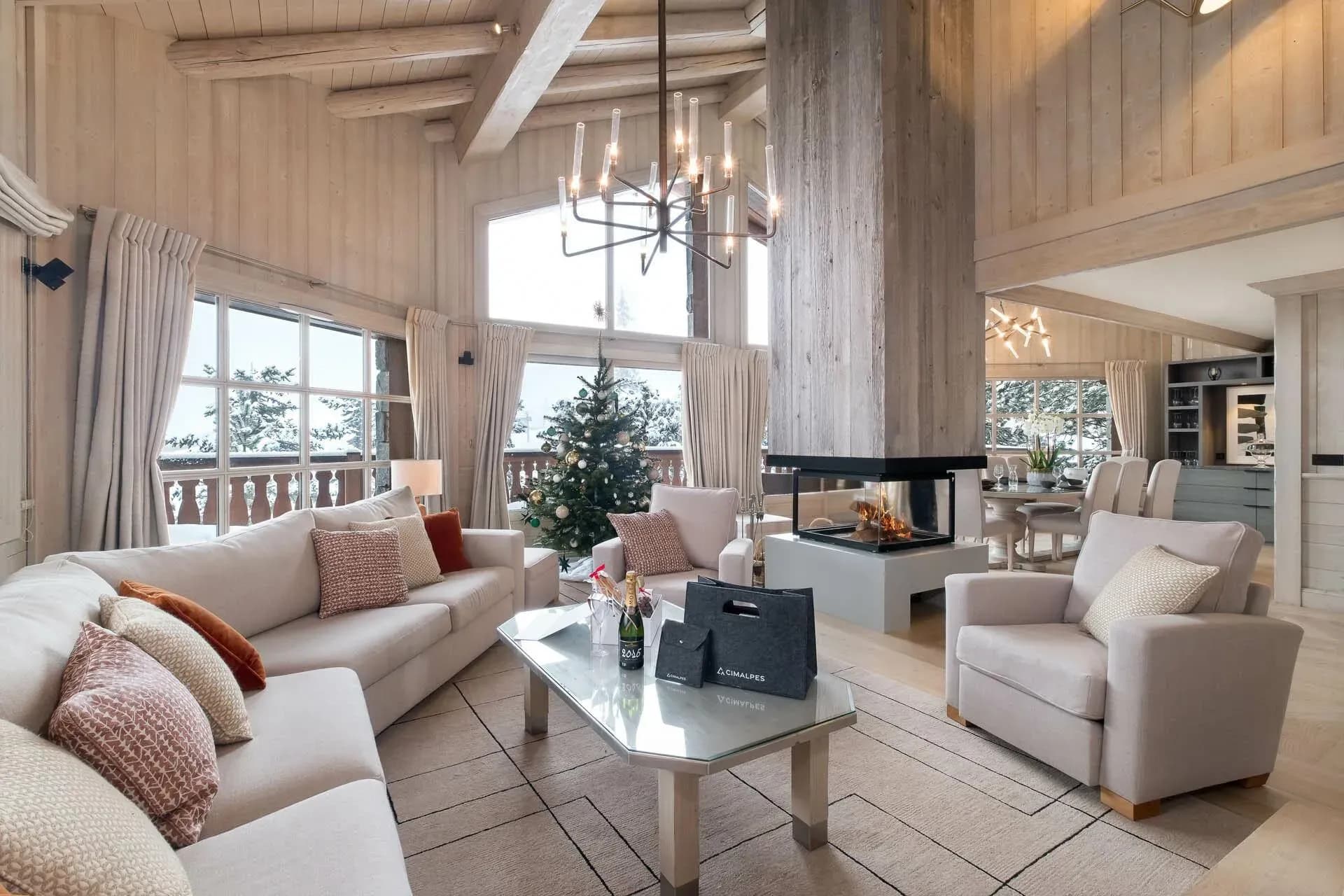 Living room with three-sided fireplace, dual sofas, and floor-to-ceiling windows with mountain views