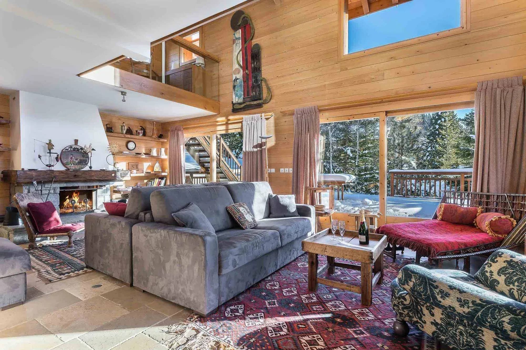 Living room with grey sofa, open fireplace and double-height wooden ceiling