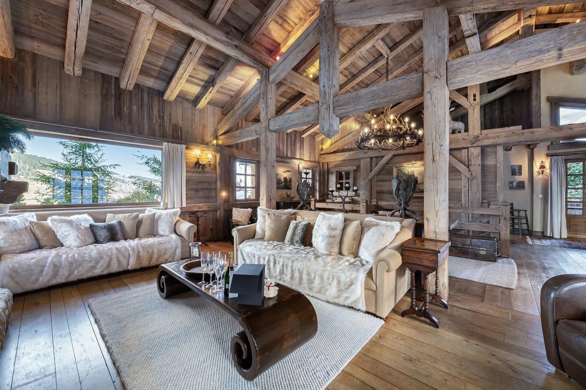 Great room with exposed beam ceiling, dual sofas, and lake views through large windows