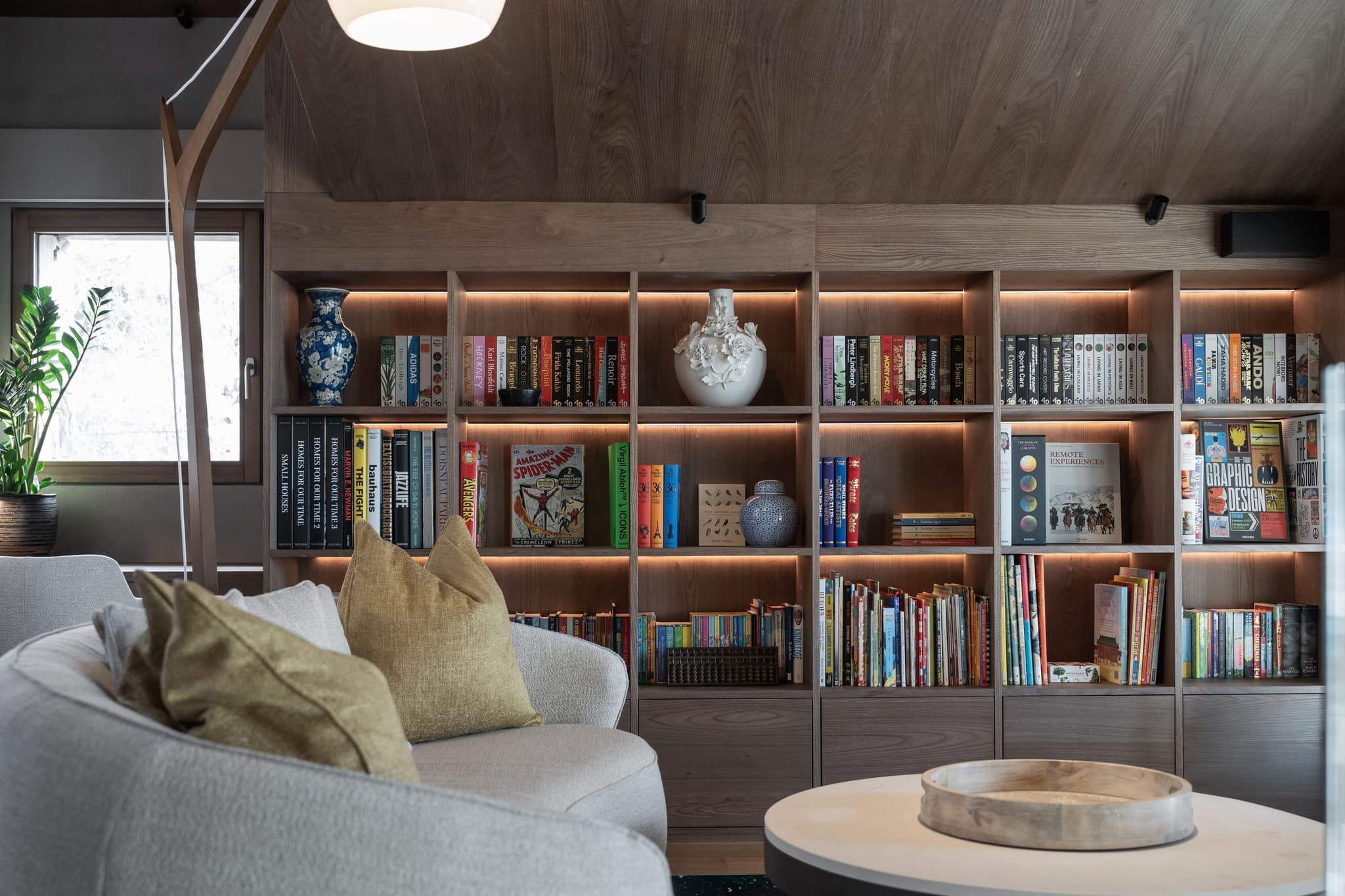Living room with built-in shelving, ambient lighting, and seating for 4+