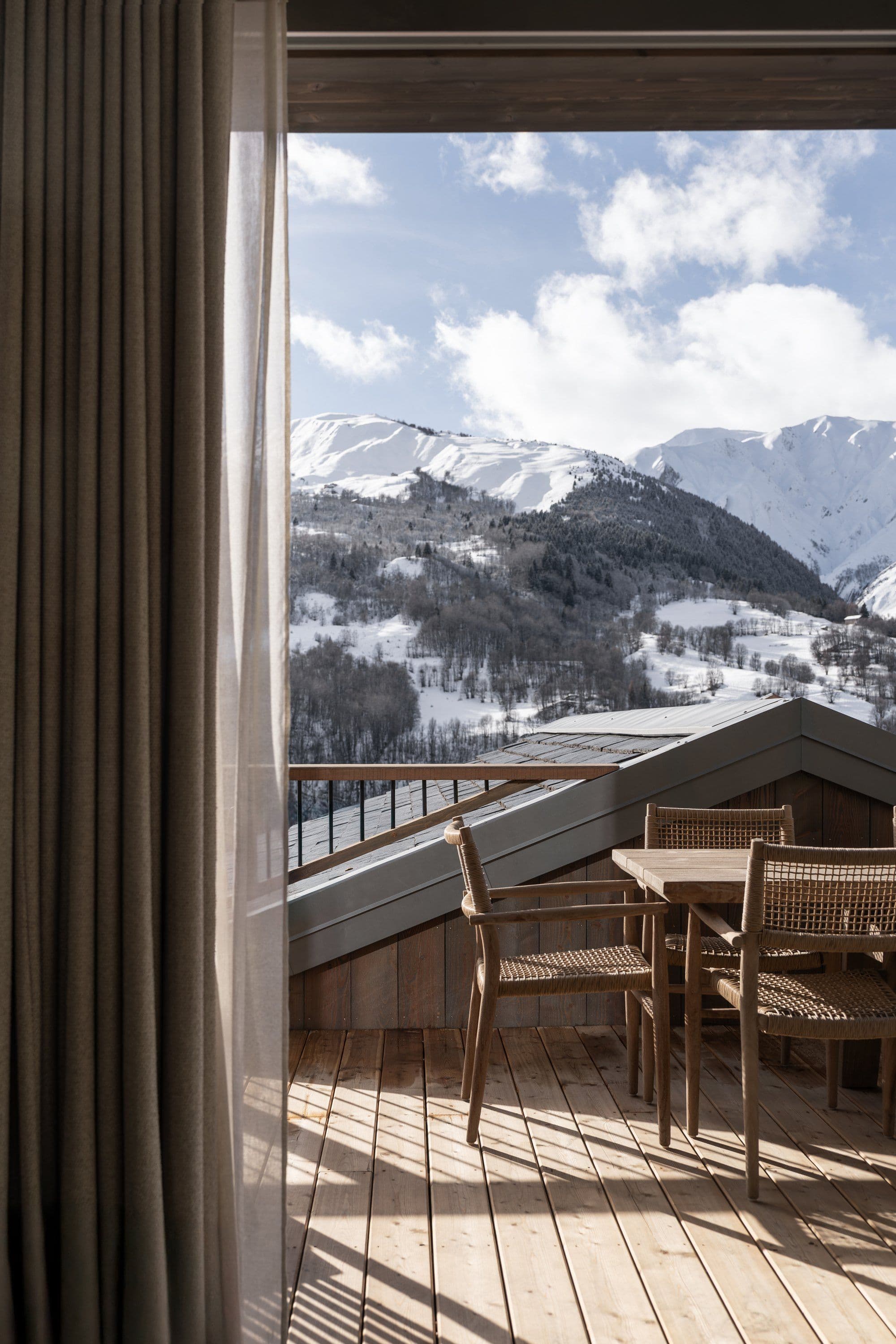 Deck with dining seating overlooking snow-covered valley and mountain peaks