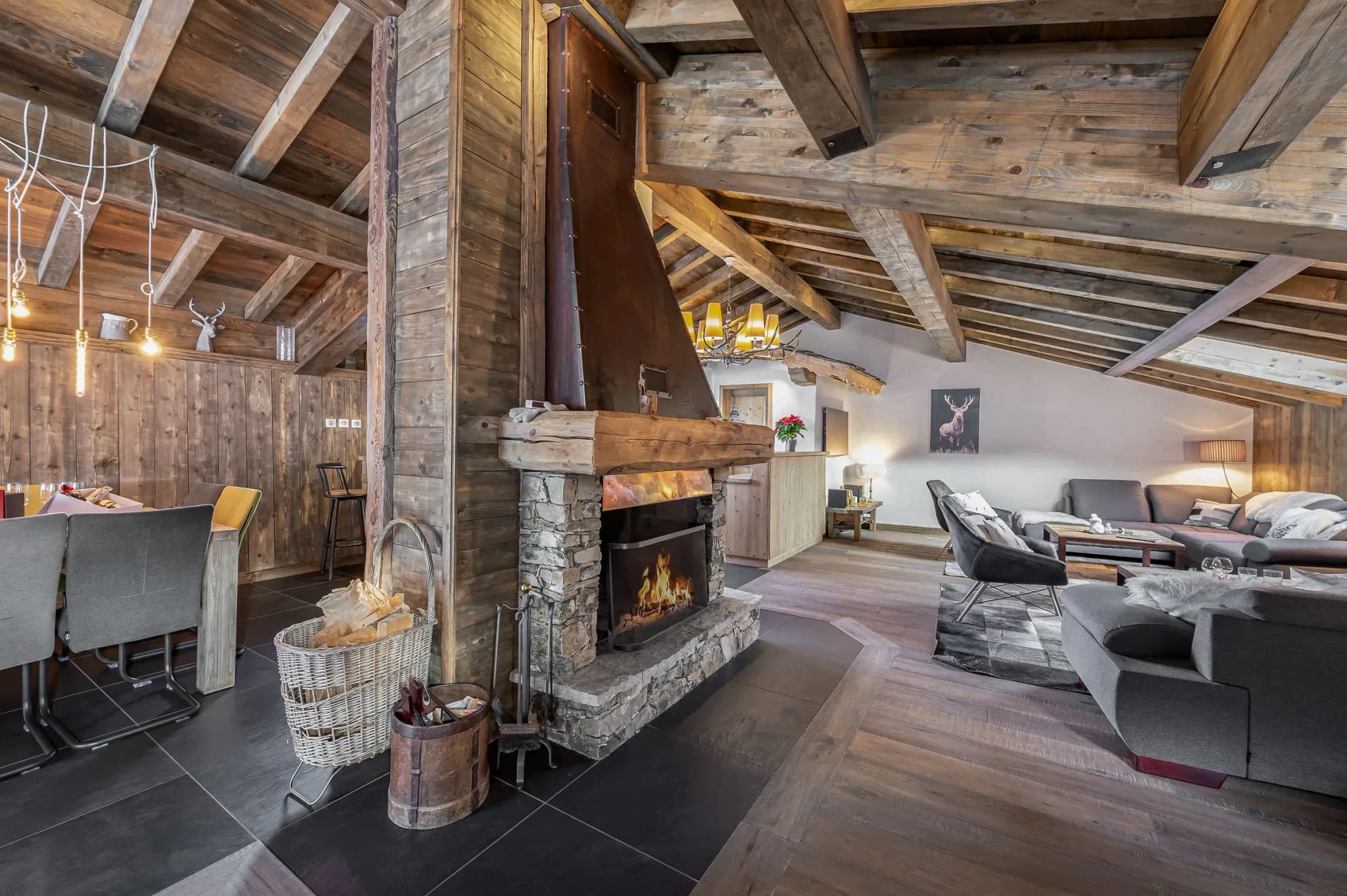 Living area with central stone fireplace, sofas and dining table beyond