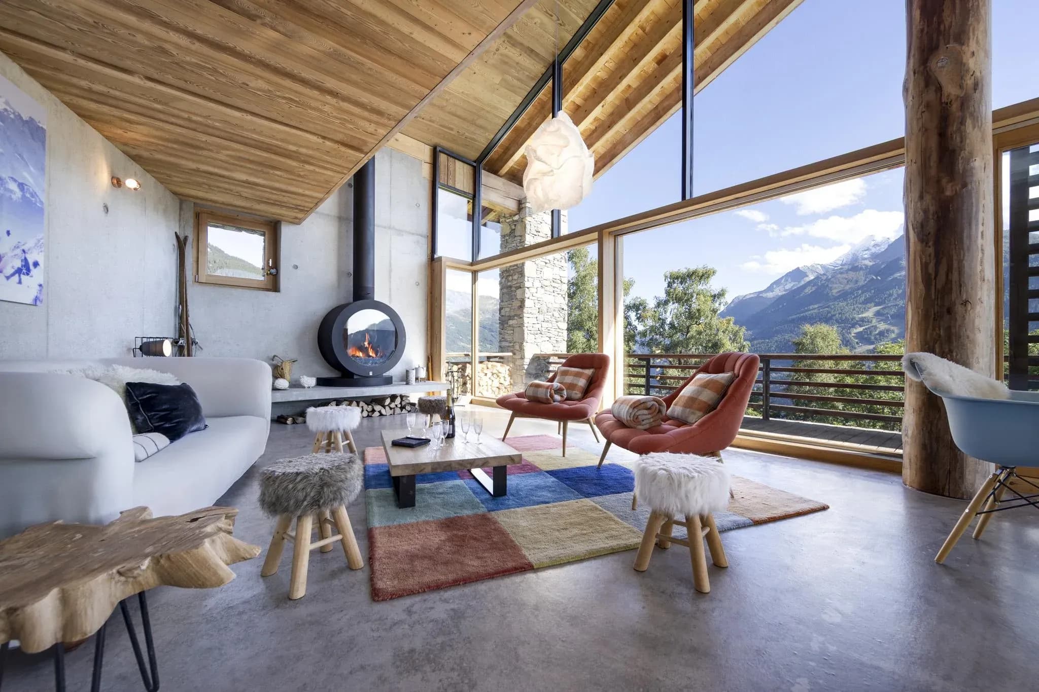 Living room with round wood stove, sofa and armchairs facing mountain views
