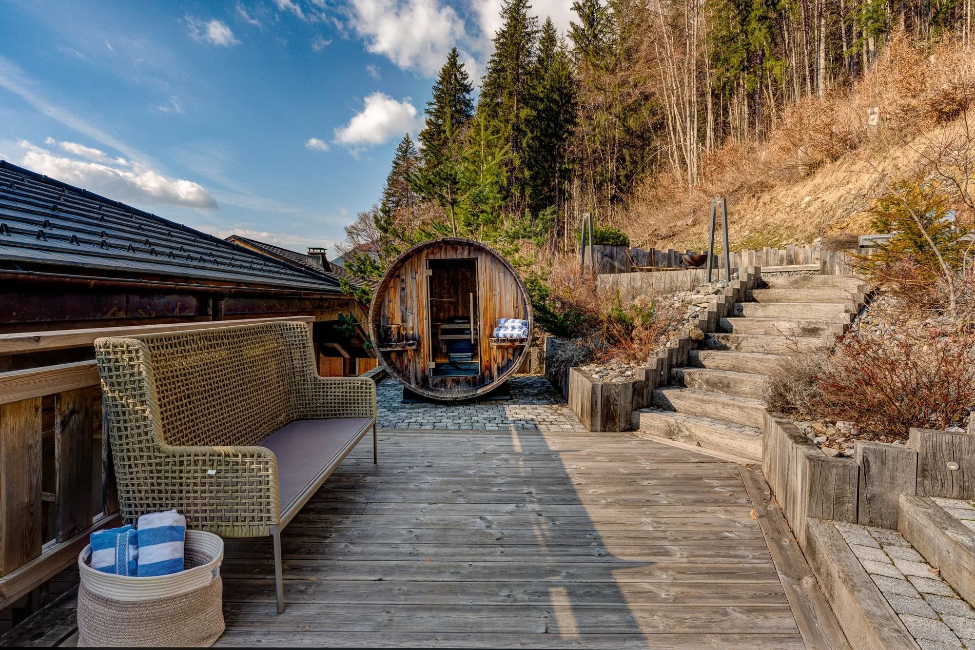 Spa deck with barrel sauna, lounge seating, and tiered wooden steps